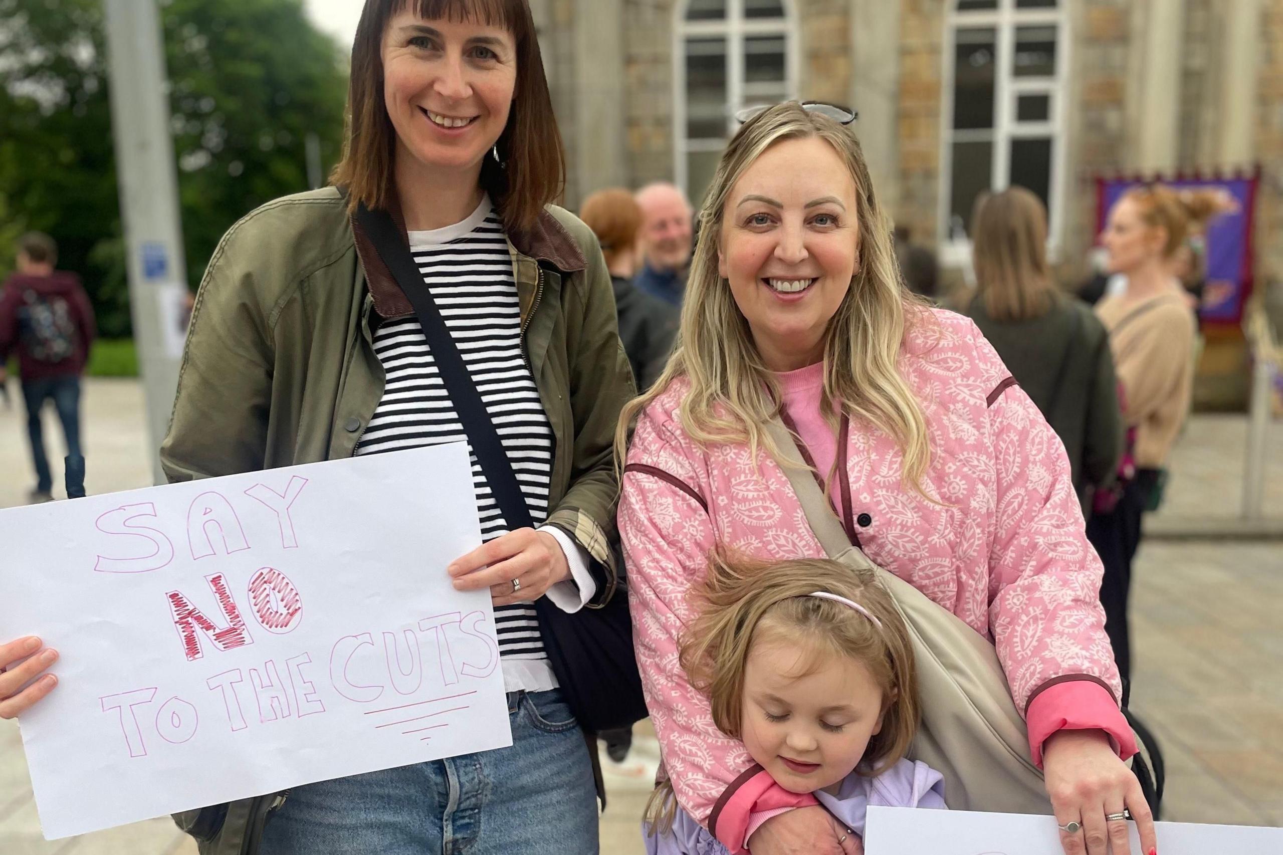 Two parents and a pupils protesting against teacher cuts