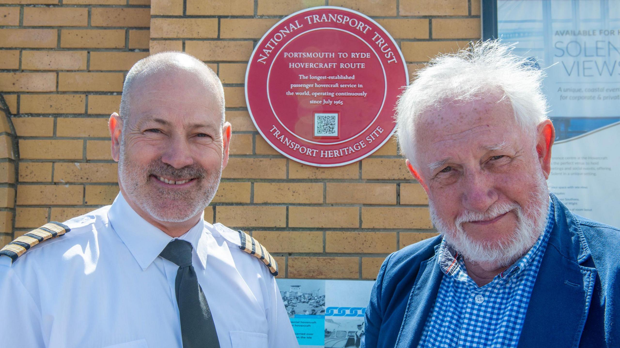 Two men stood in front of the red plaque