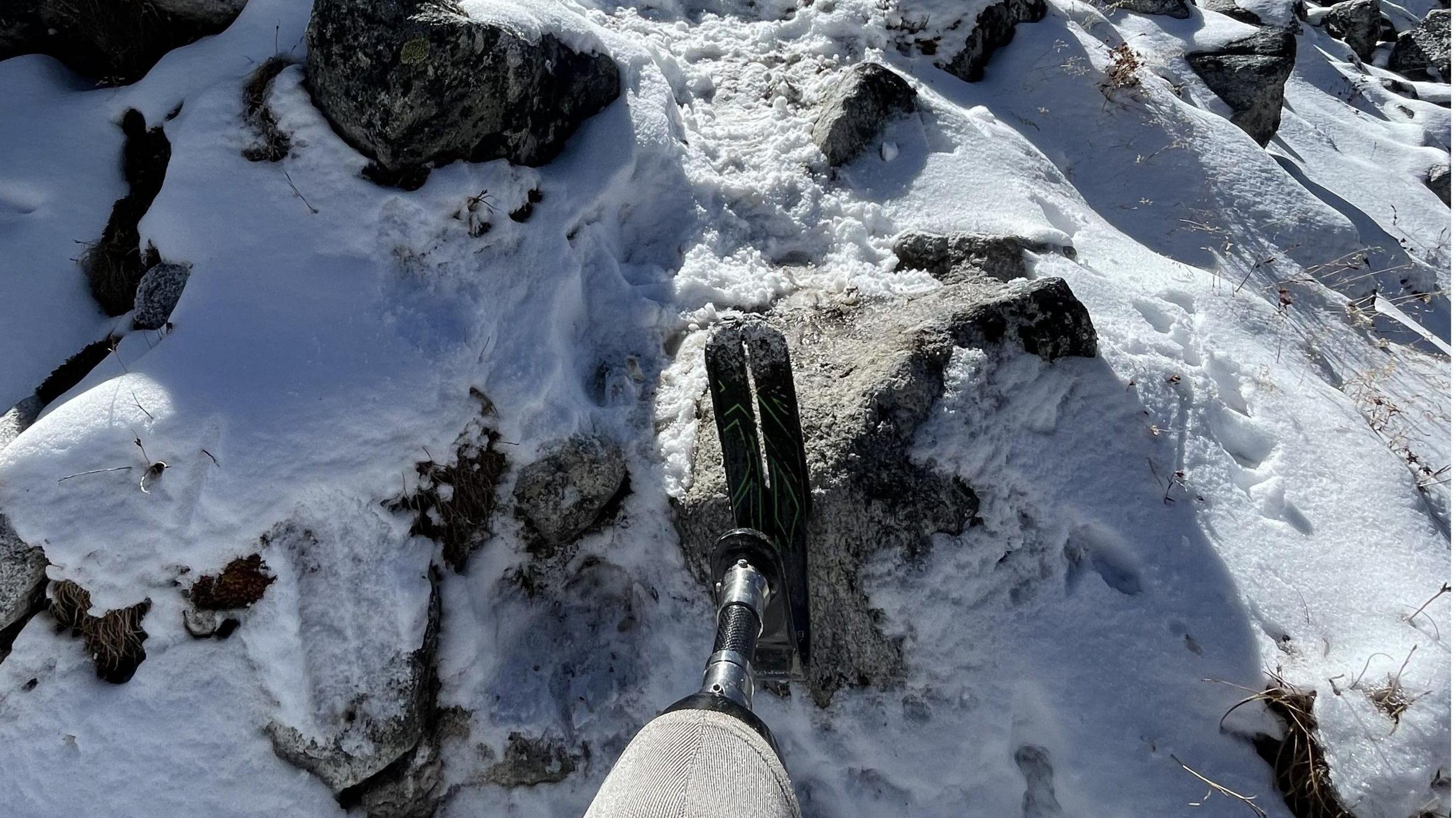 An artificial leg and foot planted in snow and rocks. 