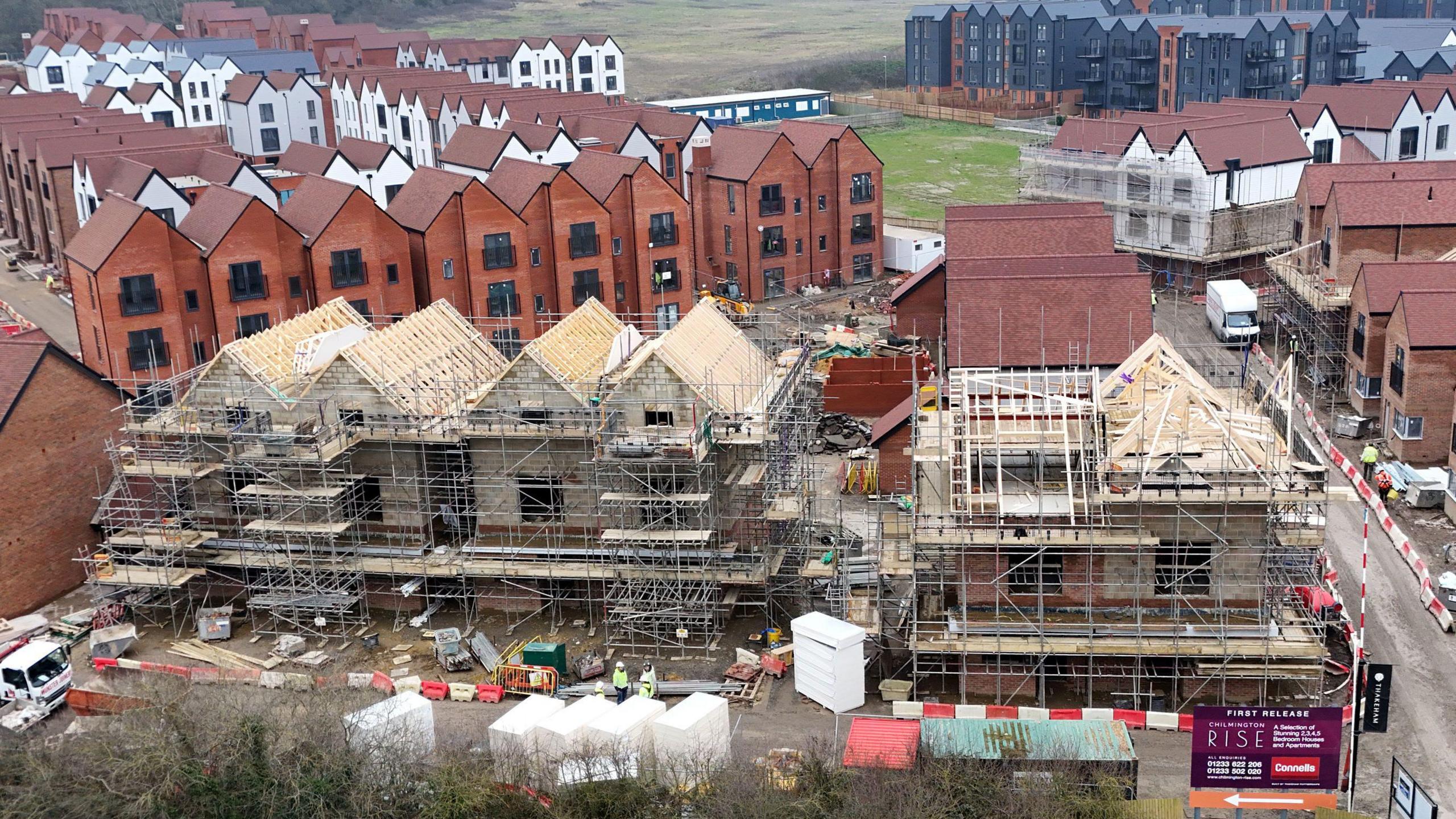 A partially built housing estate. In the background, a lot of flats have been completed. But in the foreground we can see construction work is taking place on more buildings.