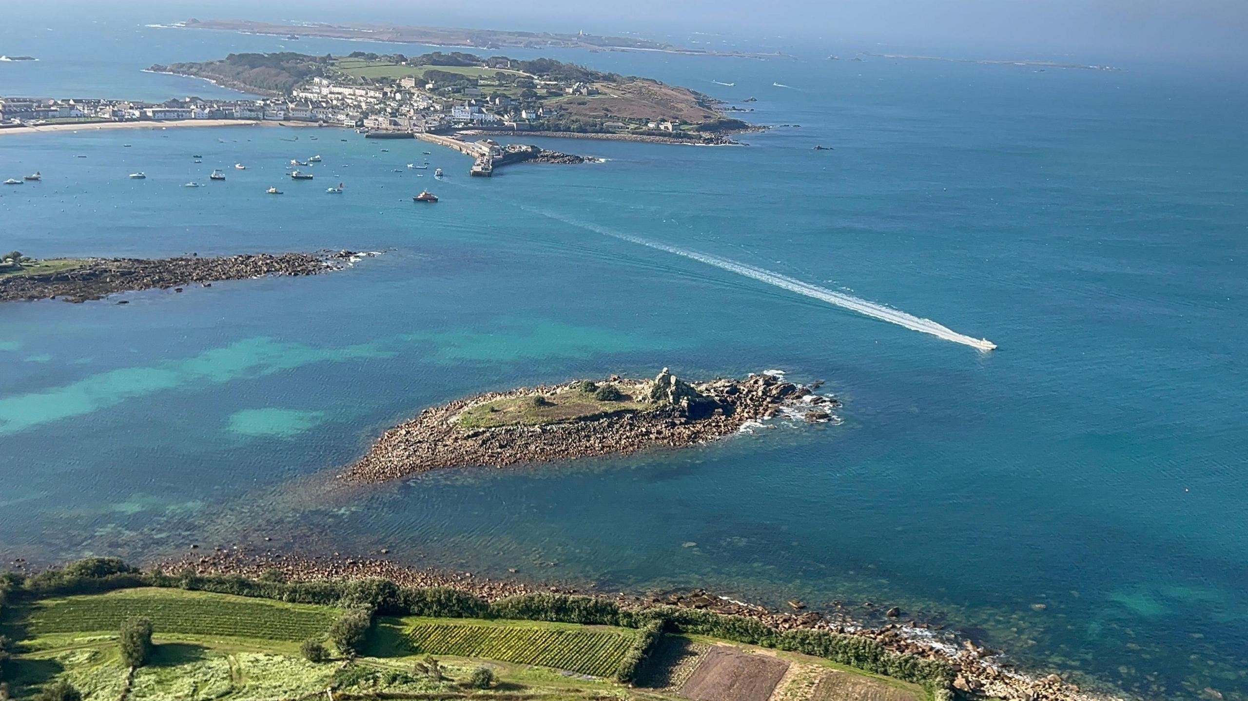 Aerial view of the Isles of Scilly on a sunny day with clear blue waters surrounding a cluster of islands