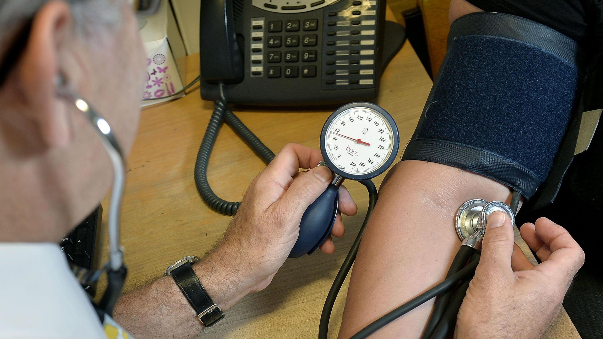 We can see a doctor checking a for a patient's blood pressure.