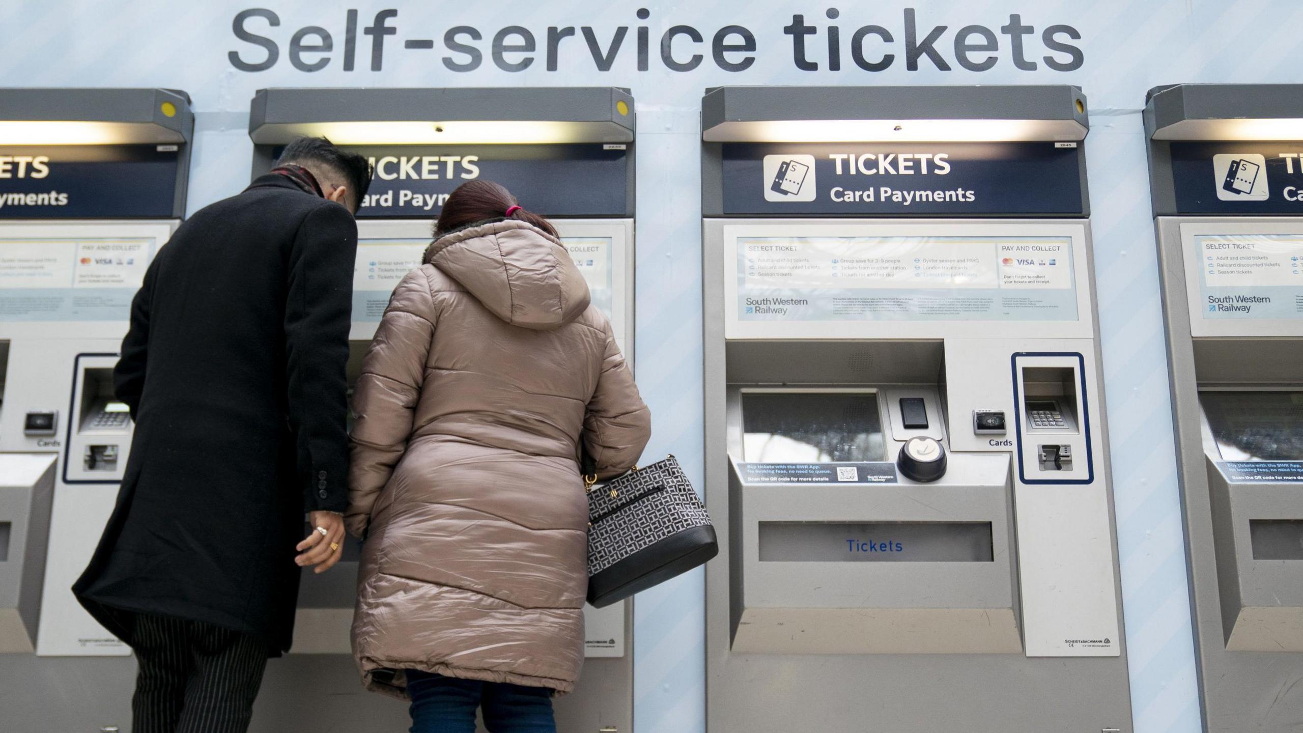 People using a ticket machine at Waterloo train station in London.