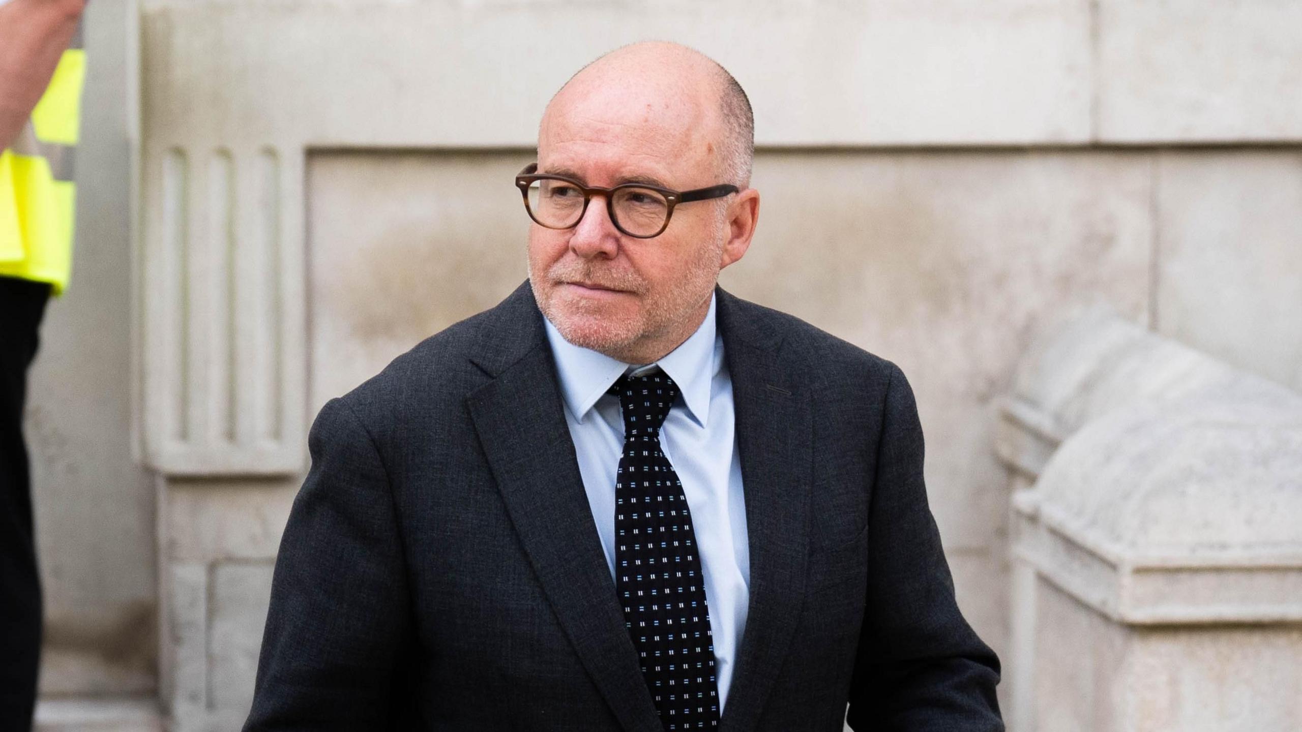 Attorney General Lord Richard Hermer leaves the Cabinet Office on Whitehall. He is wearing a dark suit and dark, spotted tie.