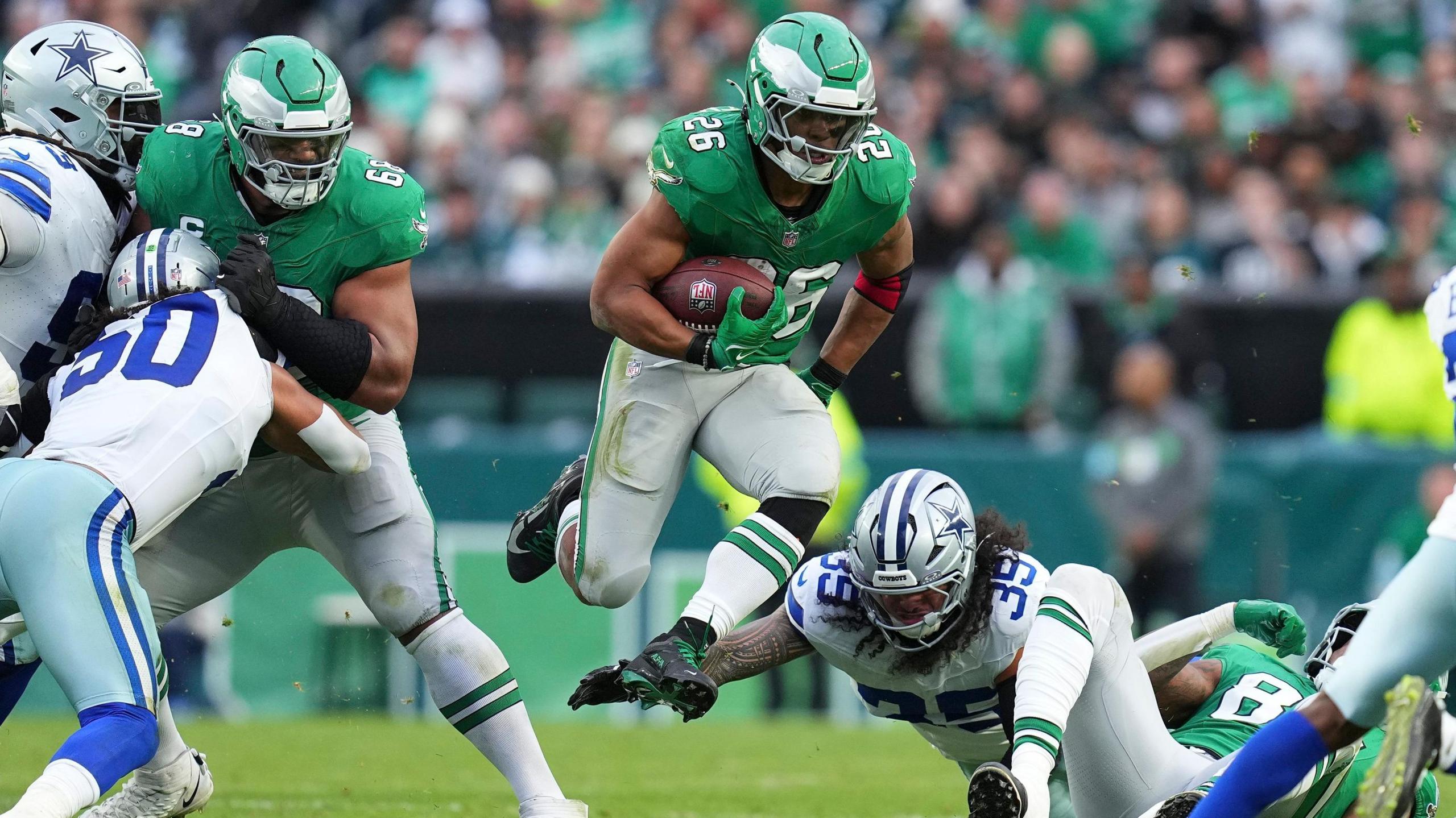 Saquon Barkley jumps over Dallas defenders as he runs during an NFL game