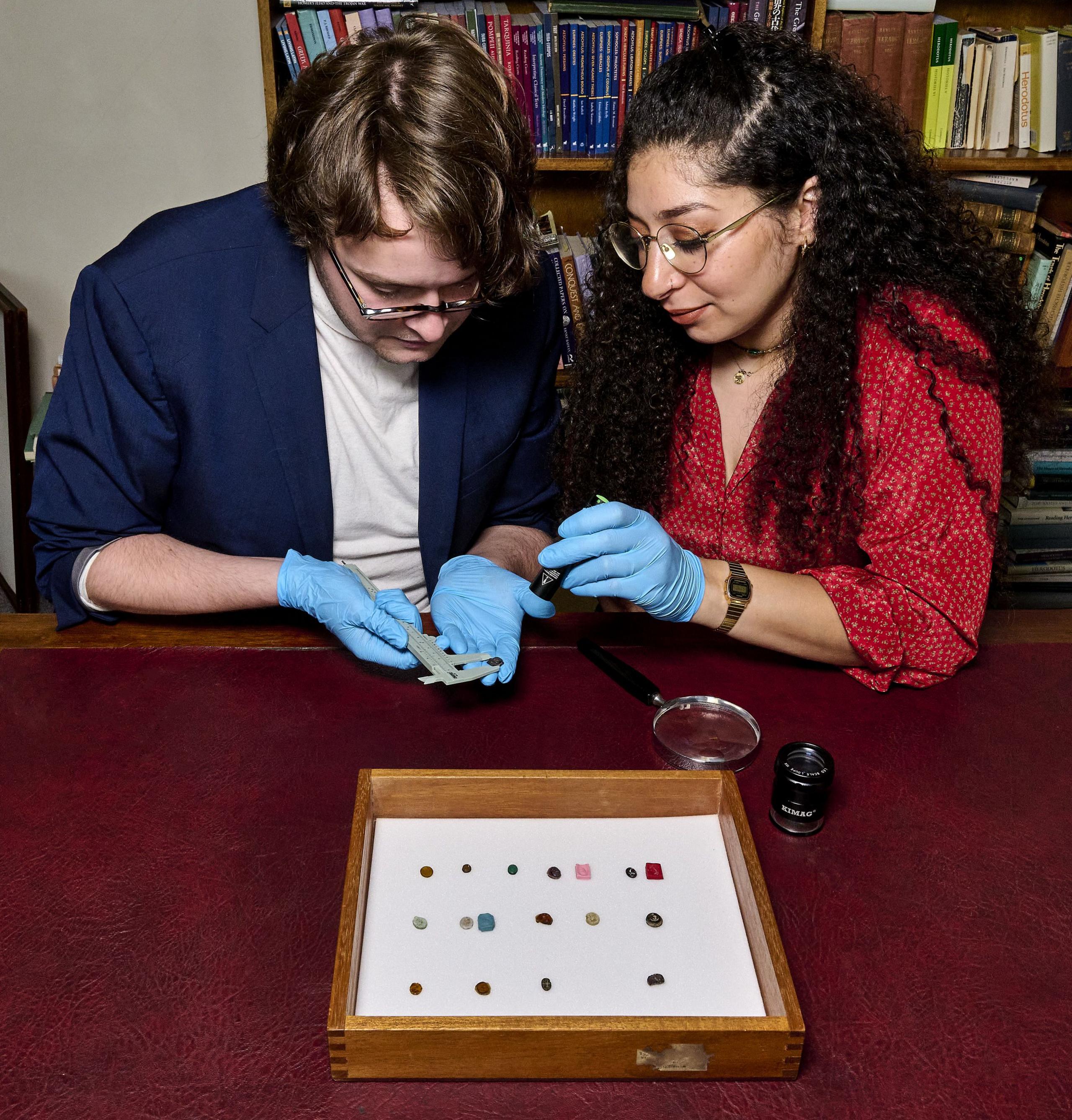 Two members of staff, a man and a woman, inspect newly recovered gemstones in the British Museum