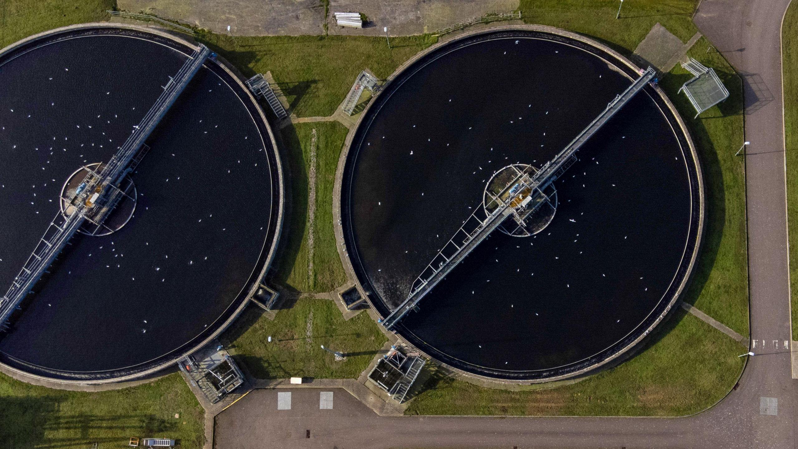 An overhead view of the huge circular settlement tanks at a wastewater treatment plant - in this case in north London - showing the arms which scrape away sludge for further treatment.