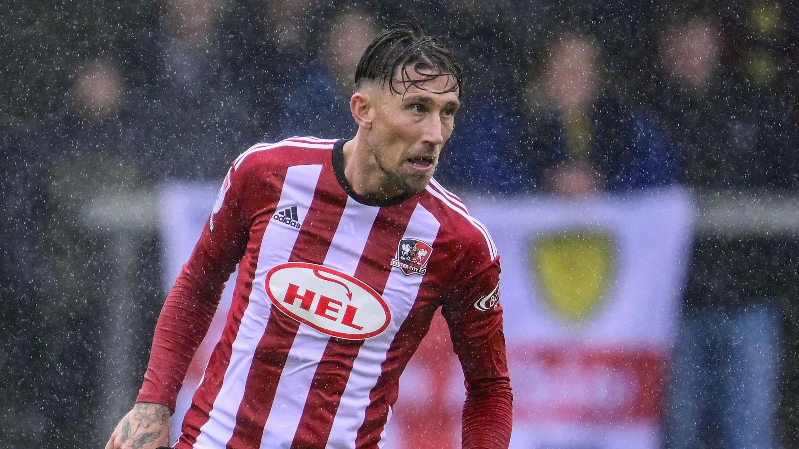 Angus MacDonald playing for Exeter last season as the rain comes down during a match
