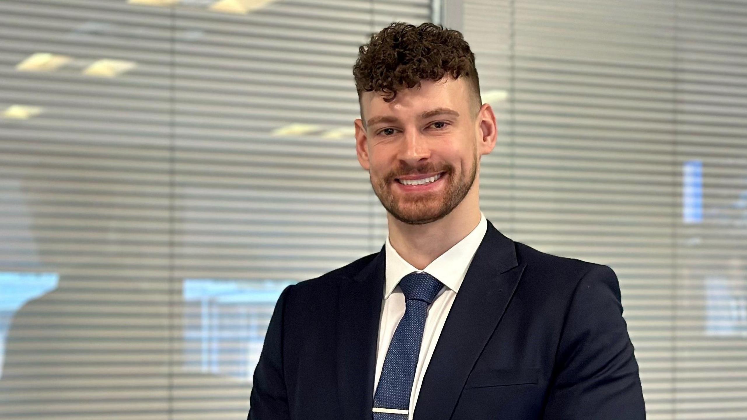 Calum Baird wearing a suit and smiling