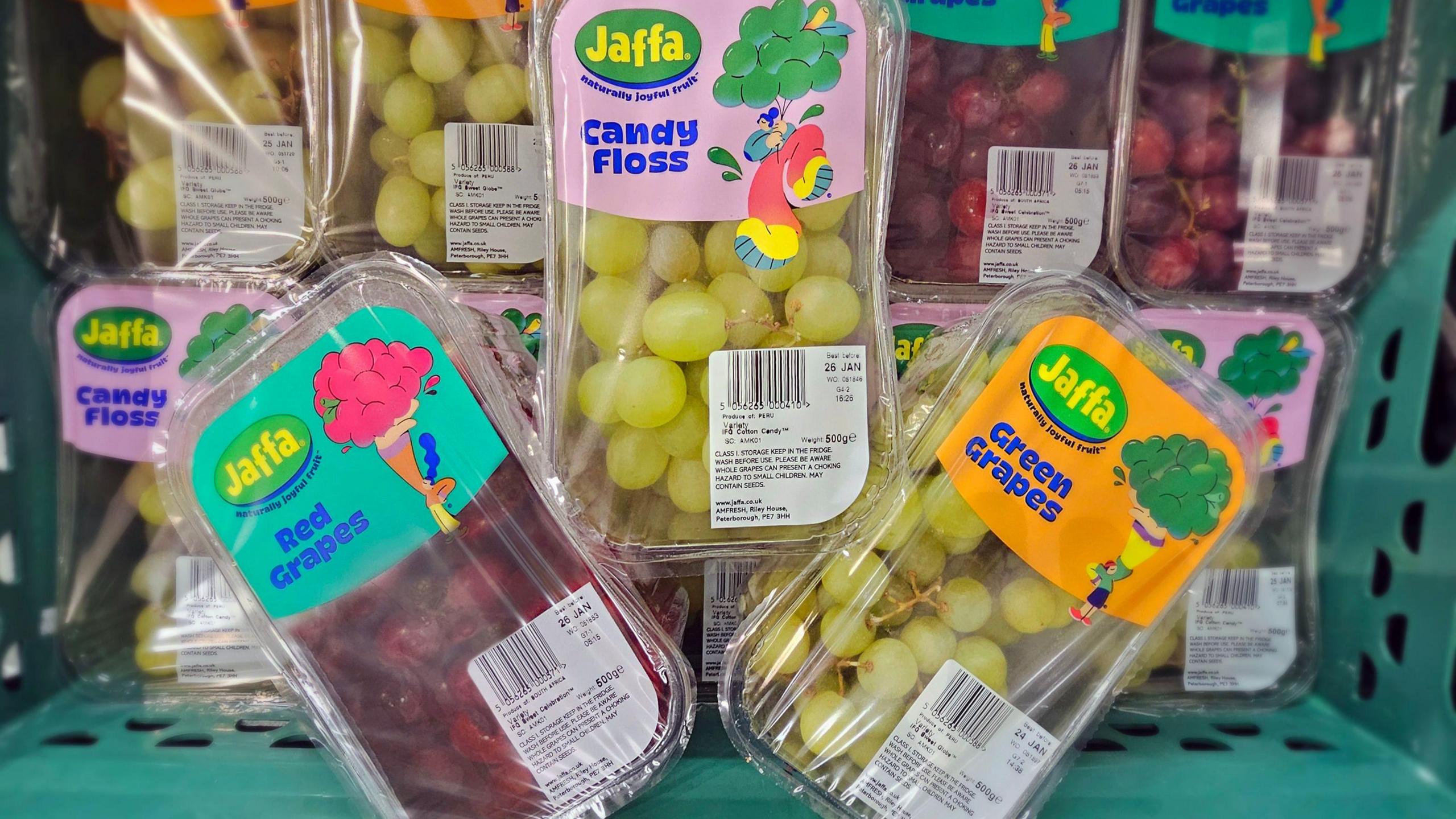 A selection of products involved in trialling the sale of grapes labelled with their flavour or texture, as it aims to better understand what customers prefer. They are in a green basket. One is red grapes, one is green grapes and the other is candy floss grapes