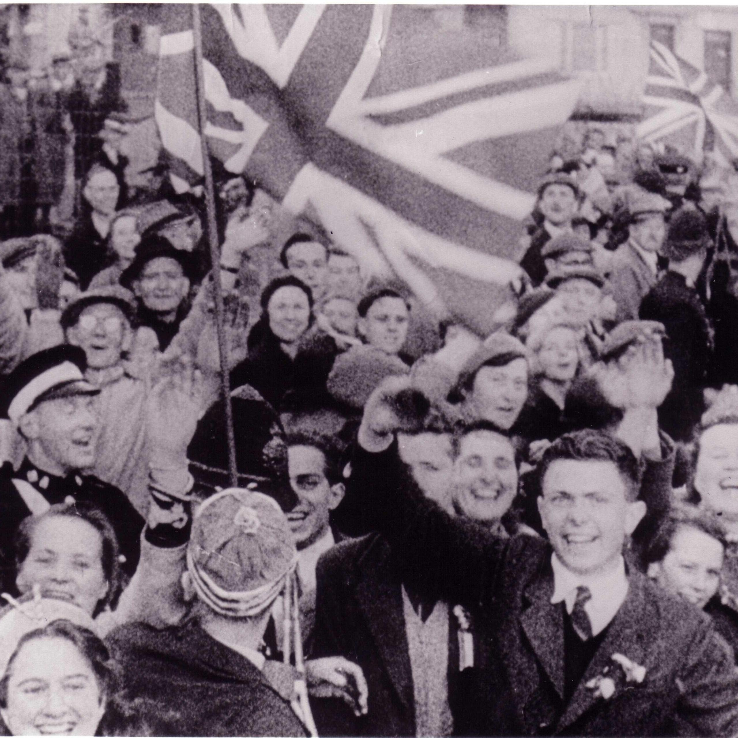 A crowd of people with smiling faces waving union flags