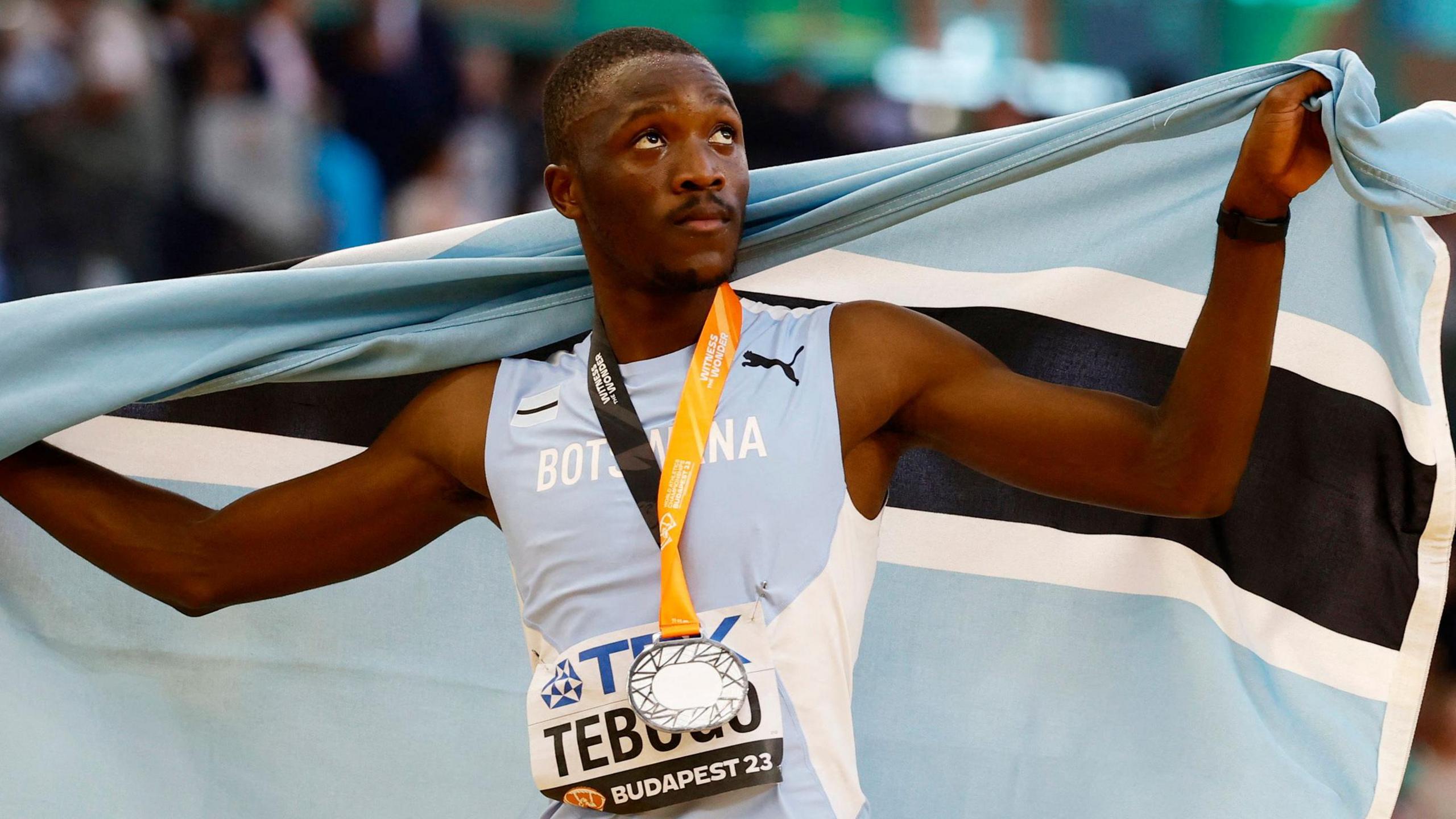 Letsile Tebogo holds a Botswanan flag as he celebrates winning a silver medal at the World Athletics Championships