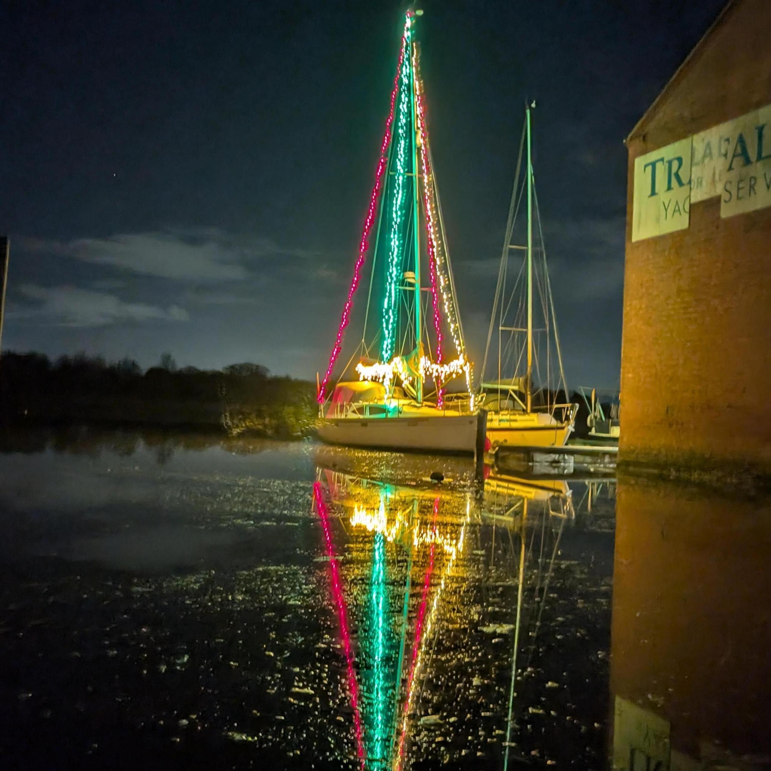 Sailing boat with Christmas lights decorating its mast and sails.