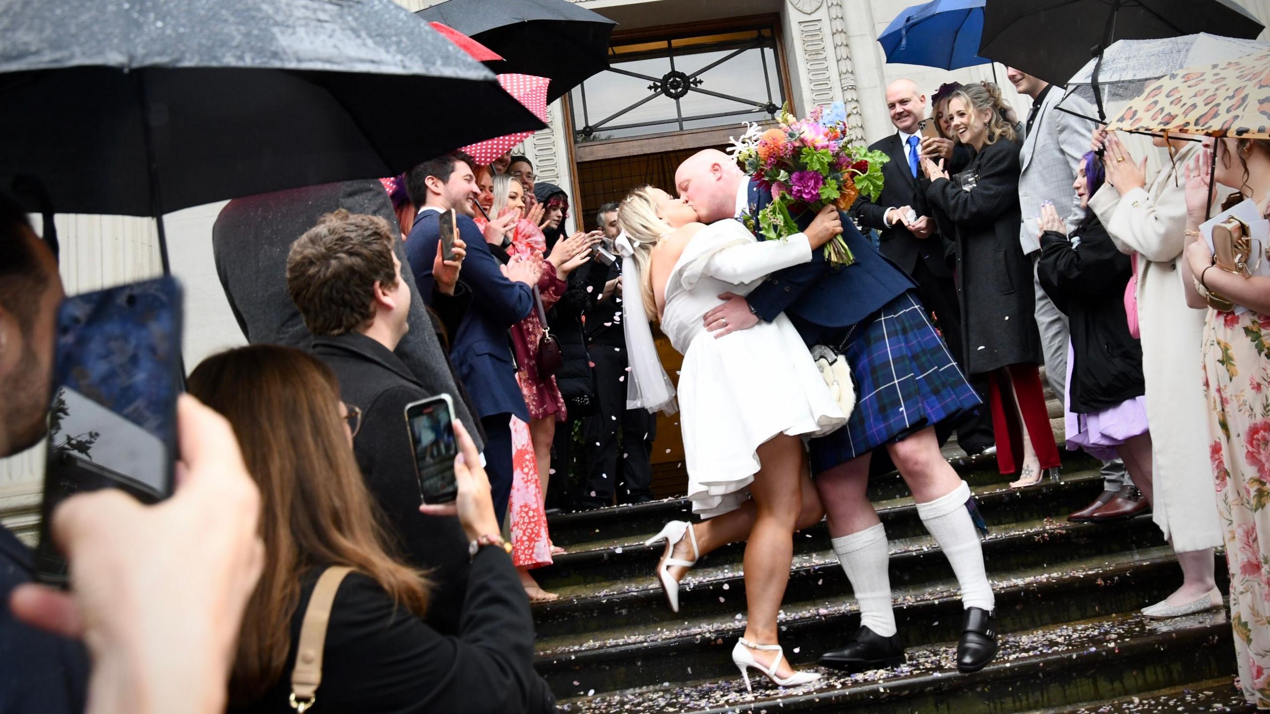 Thomas Mackintosh and Paige Evans kiss on the steps of the town hall