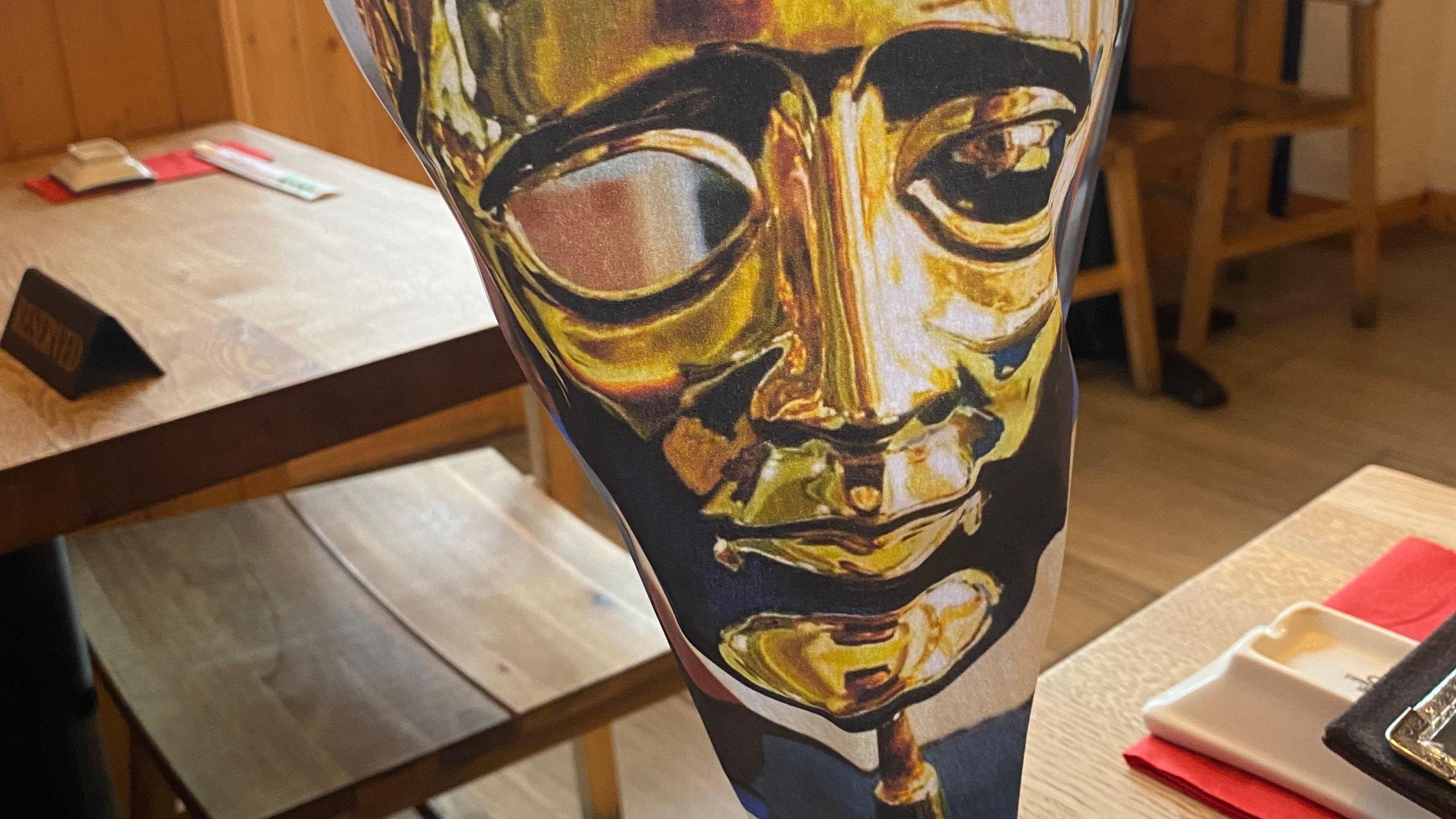 A mock Bafta award made of paper, on a wooden table inside an empty restaurant.