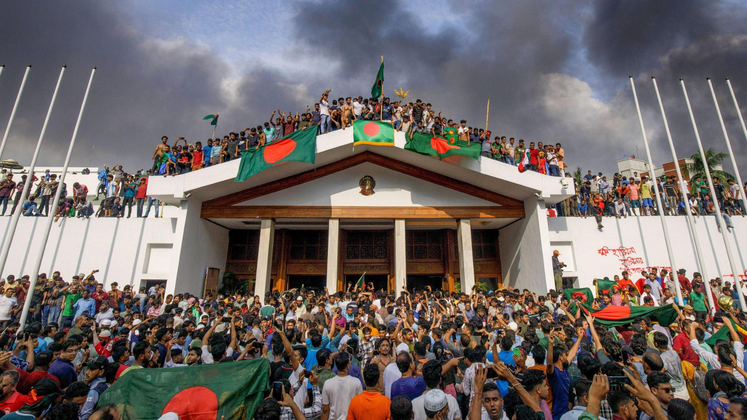 Protesters celebrating the resignation of Sheikh Hasina on 05 August in front and on the roof of the prime minister's residence