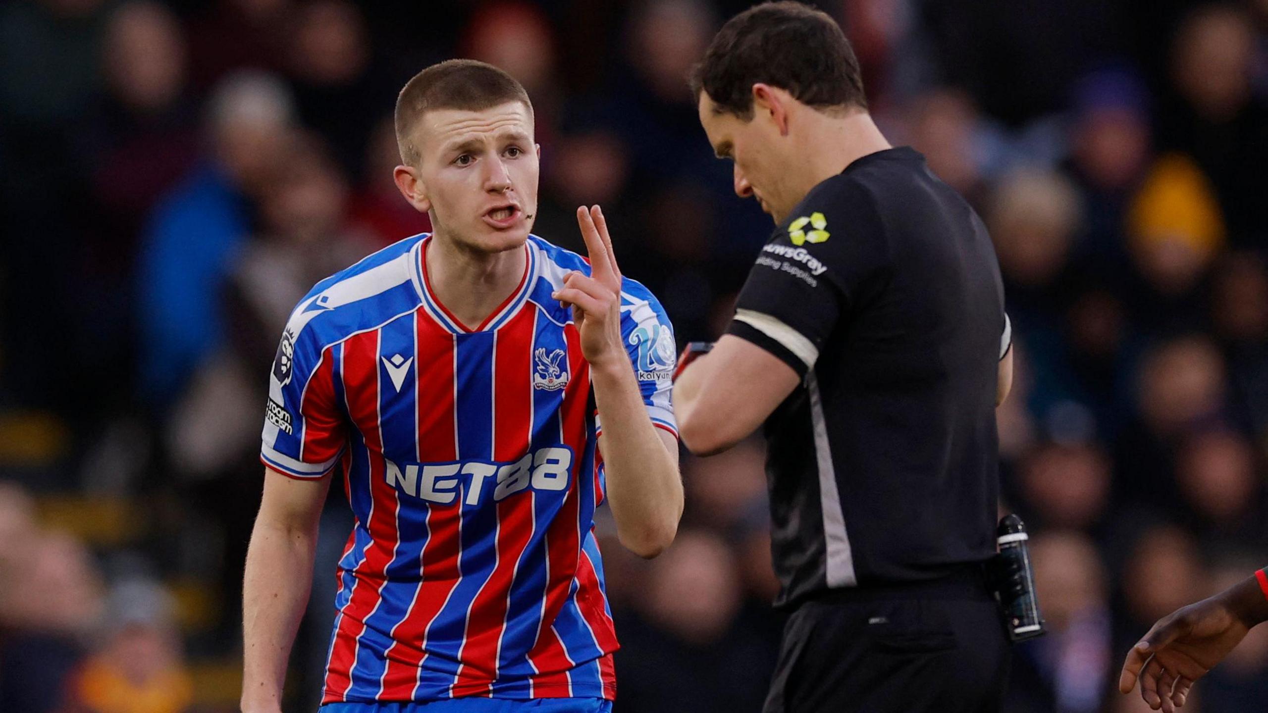 Adam Wharton holds his hand up to referee Darren England