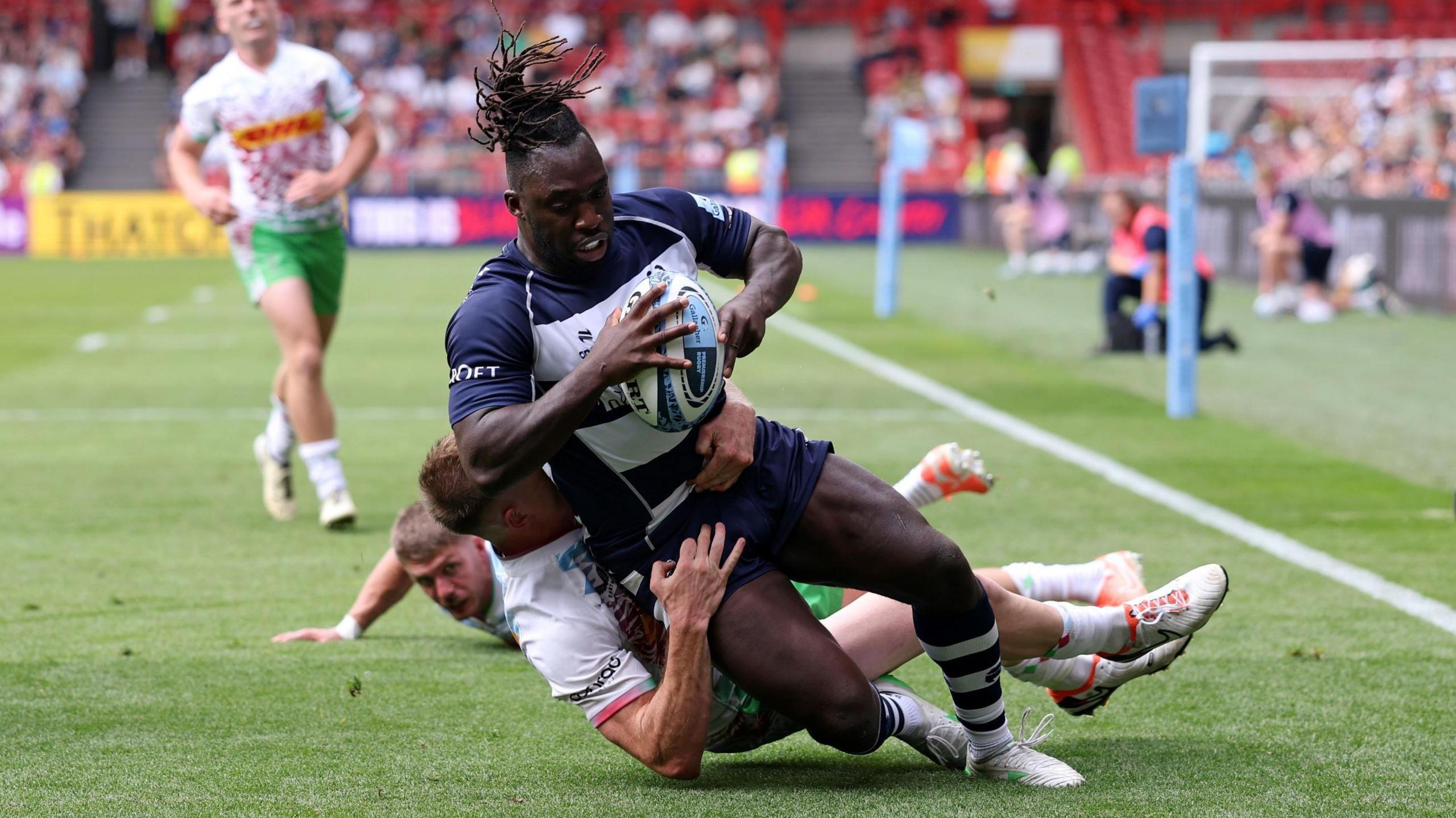 Gabriel Ibitoye of Bristol Bears grounds the ball for his team's fifth try against Harlequins despite the efforts of an opposition player to stop him