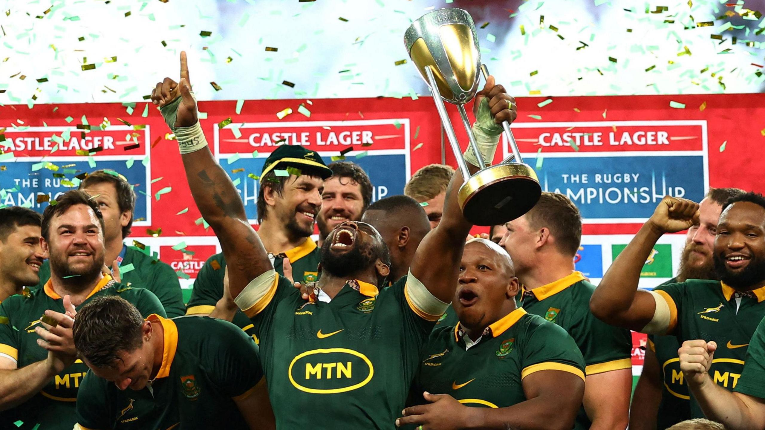 South Africa captain Siya Kolisi looks up and screams in delight as he lifts the 2024 Rugby Championship trophy, surrounded by team-mates and with ticker tape falling