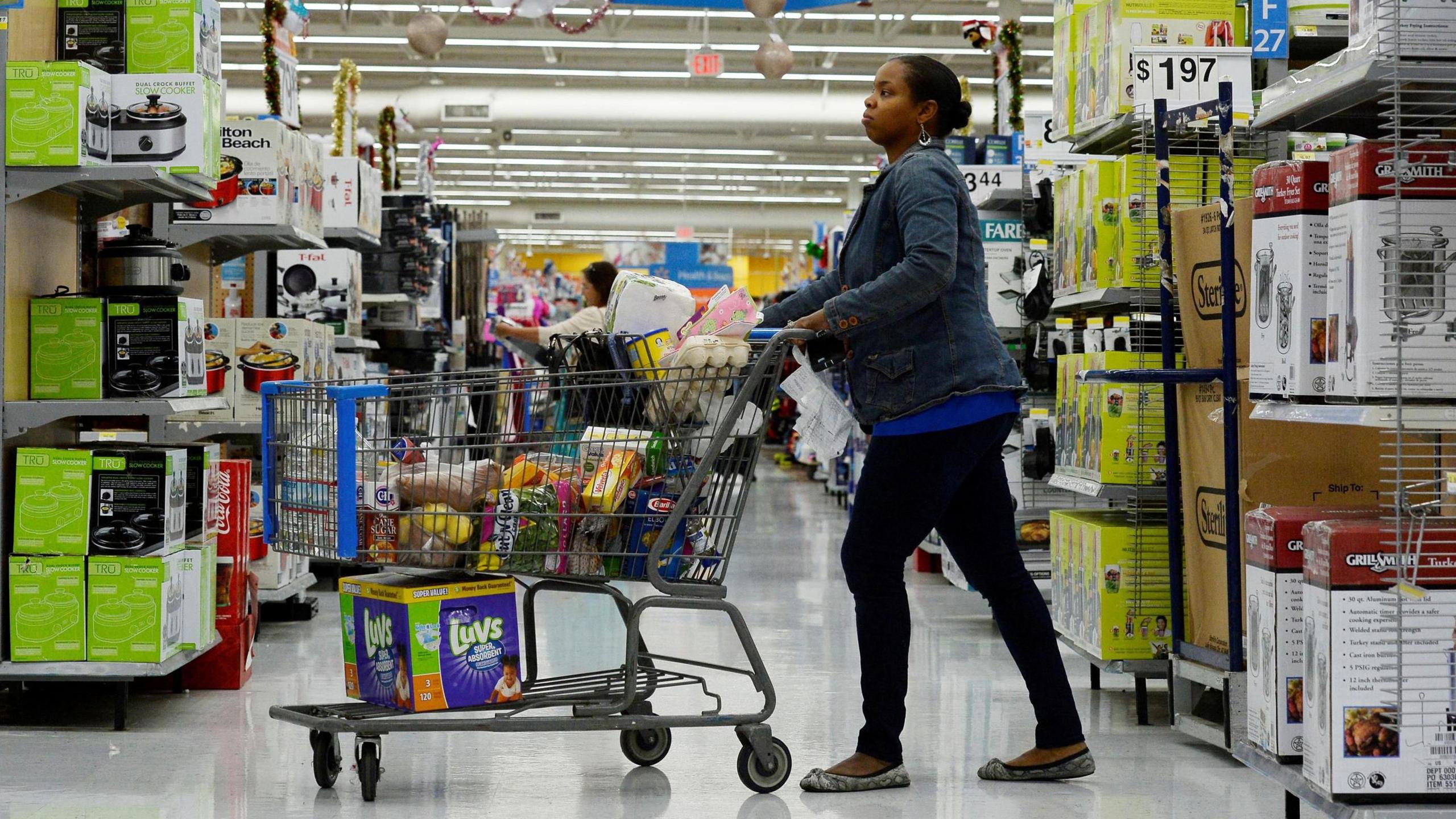 A woman pushes a trolley through a Walmart supermarket