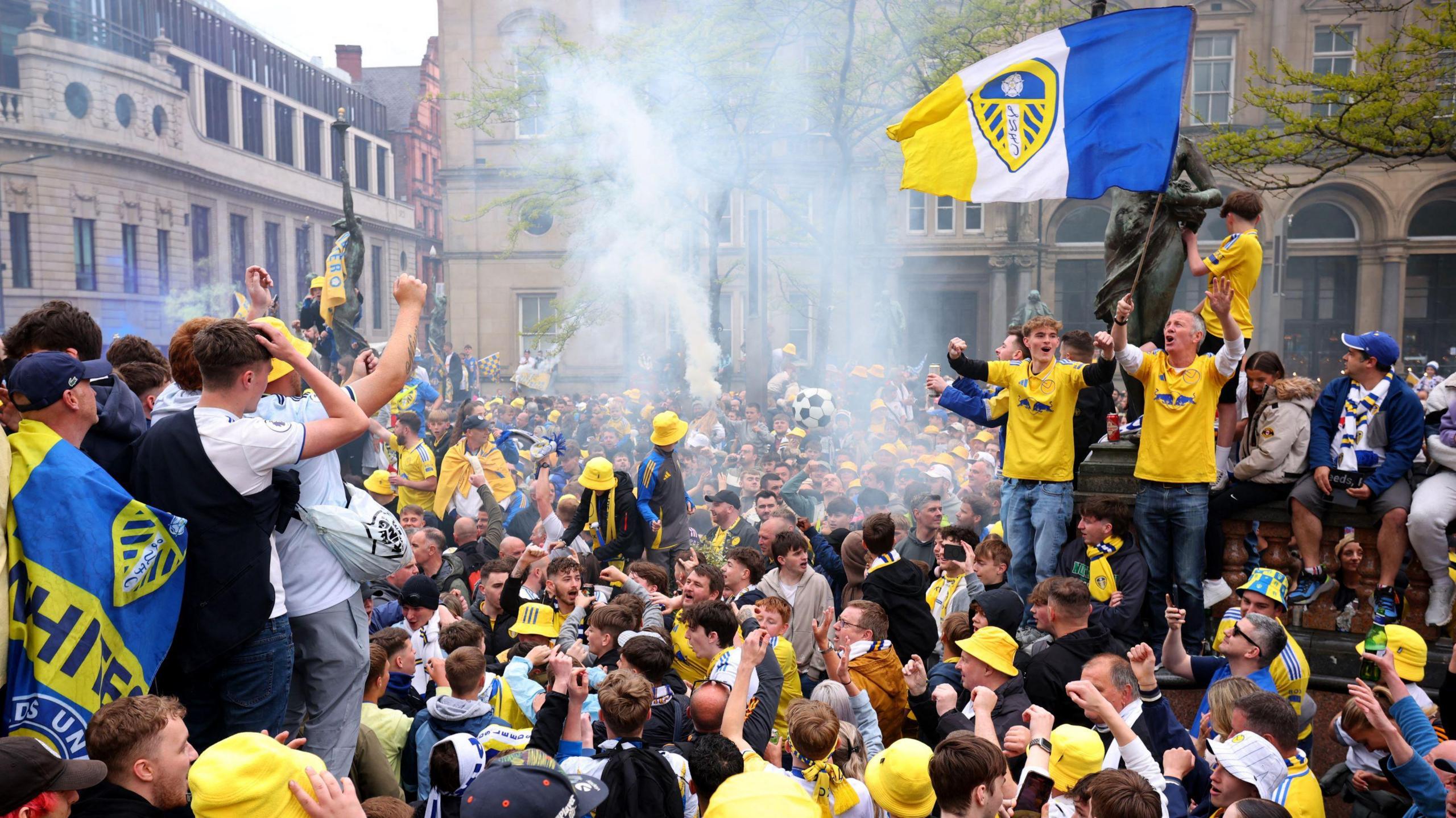 Flares in the air and lots of fans with some holding up flags 