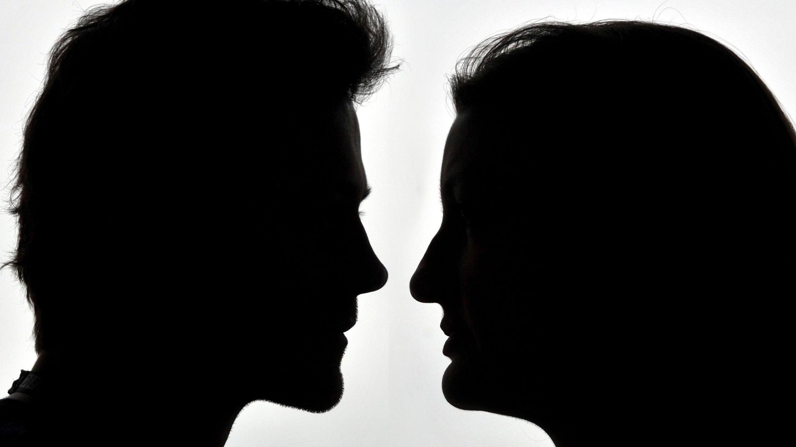 A side-profile silhouette of a man and a woman facing one another.
