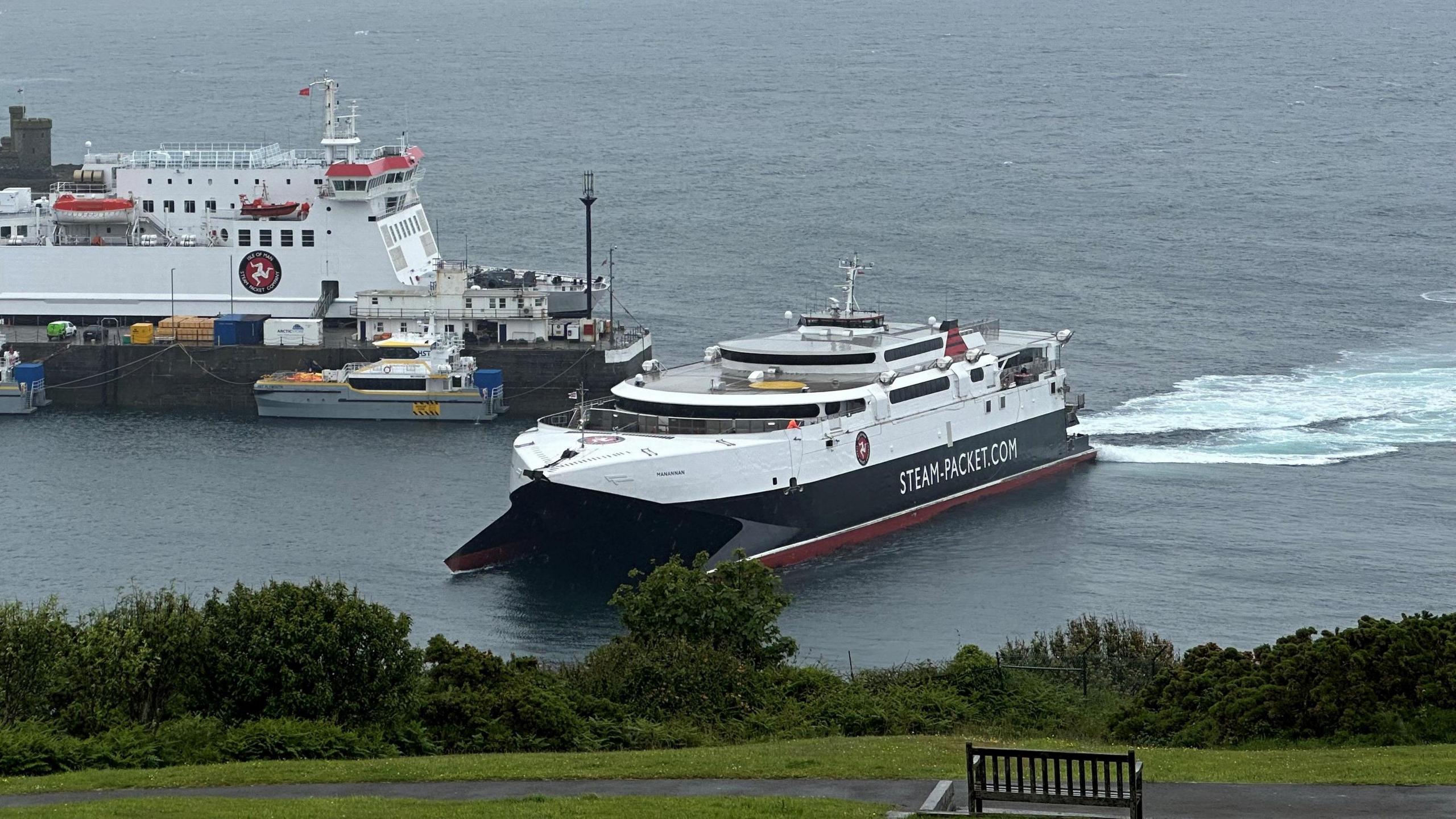 A white, black and red ferry sailing into a harbour