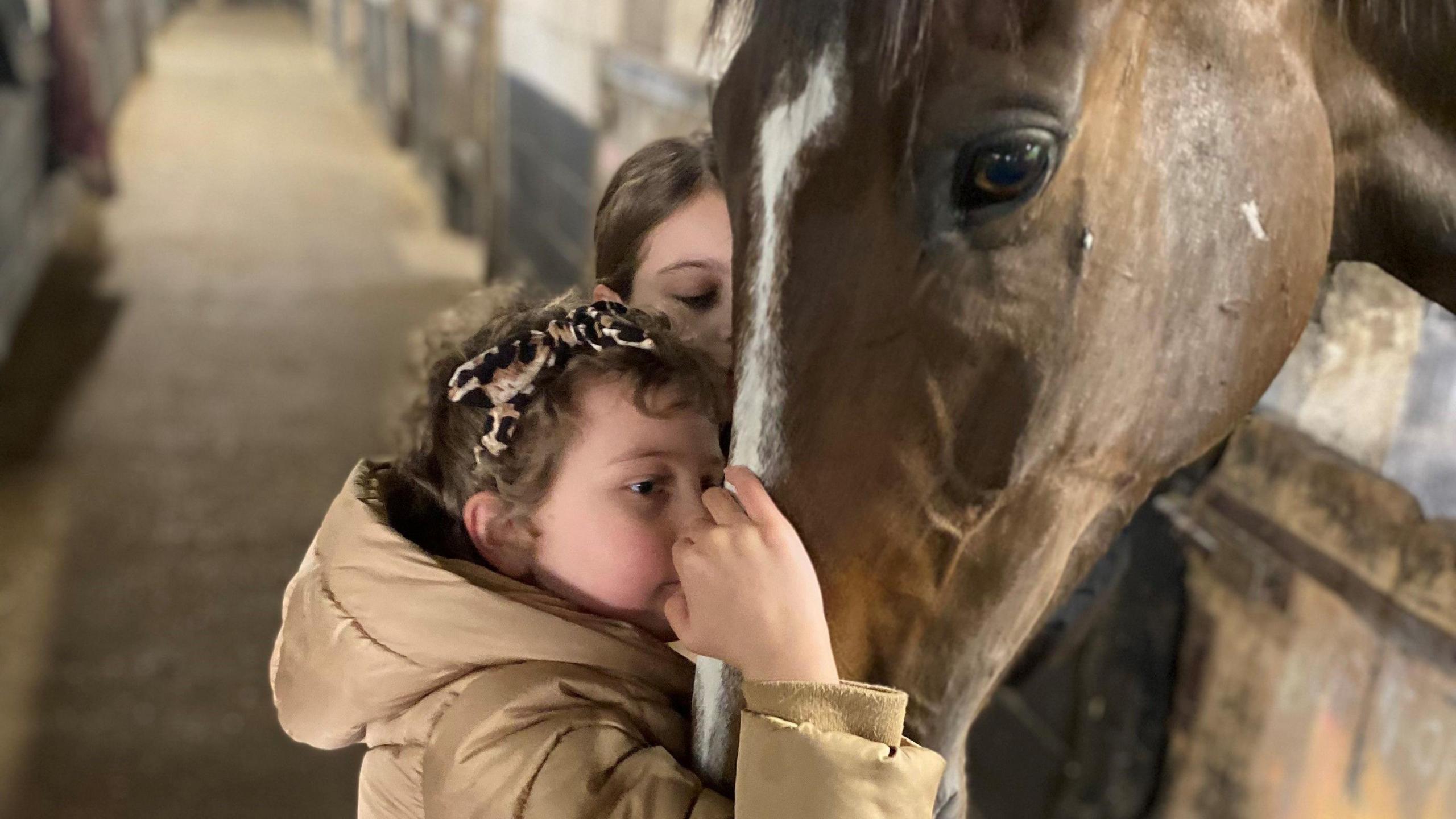 Betsy kisses Kitty's Light in the stables with her sister Tilly alongside her