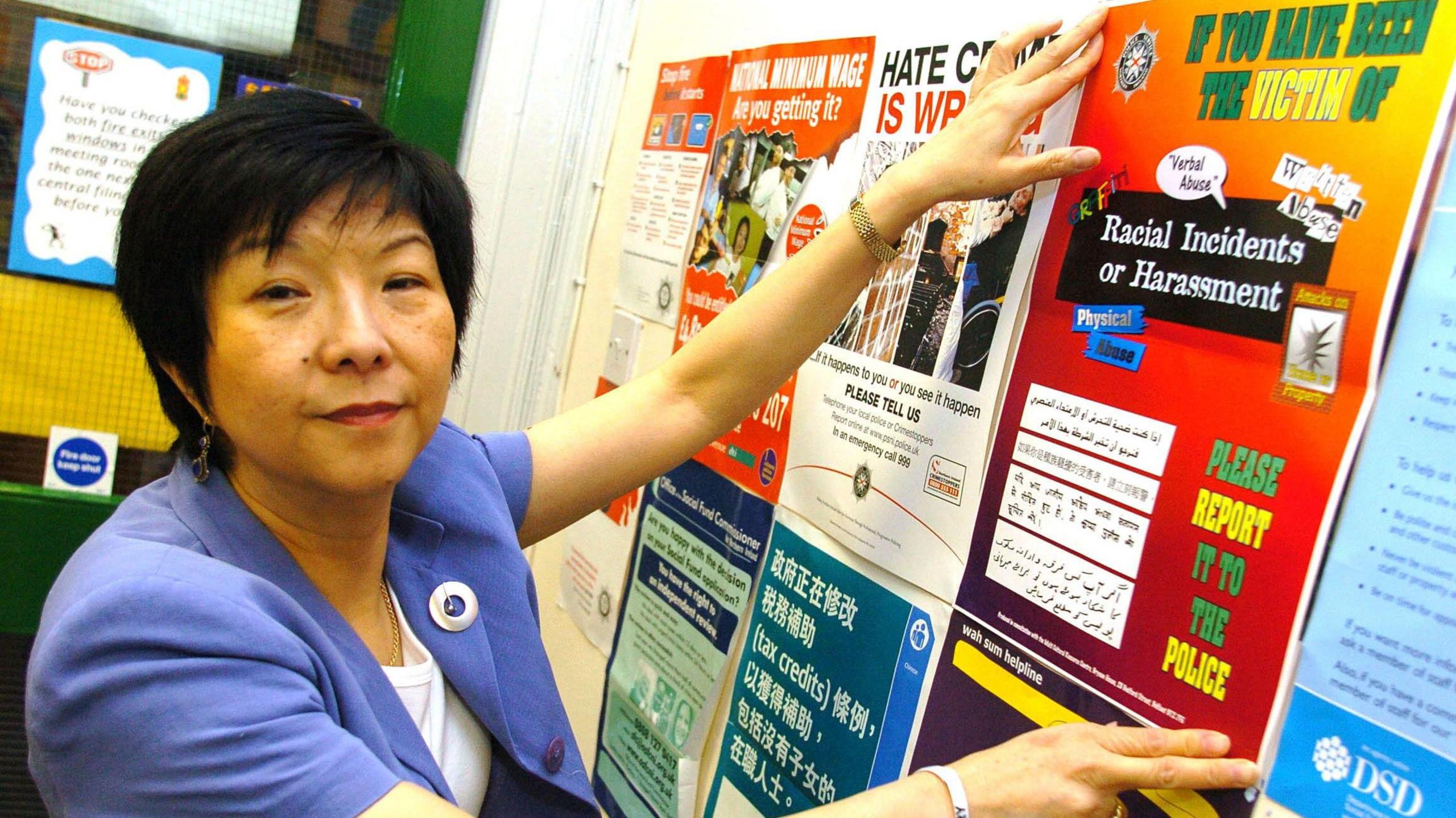 Anna Lo pictured putting up a poster on a notice board which advised the public how to report racist attacks to the police