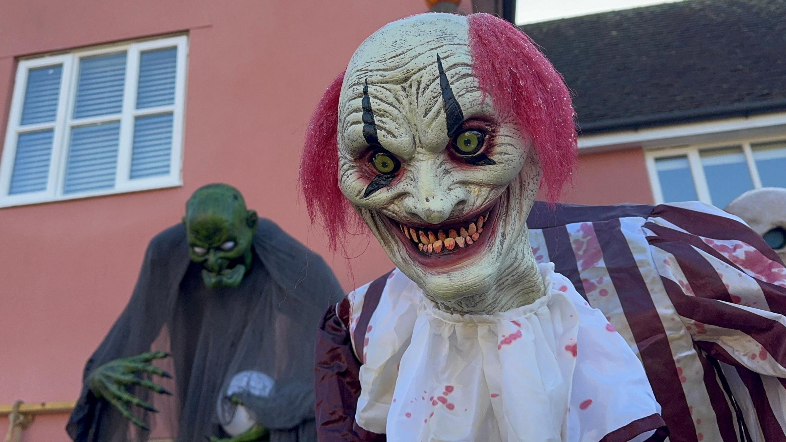 A close-up photo of a scary animatronic clown which is grinning menacingly.