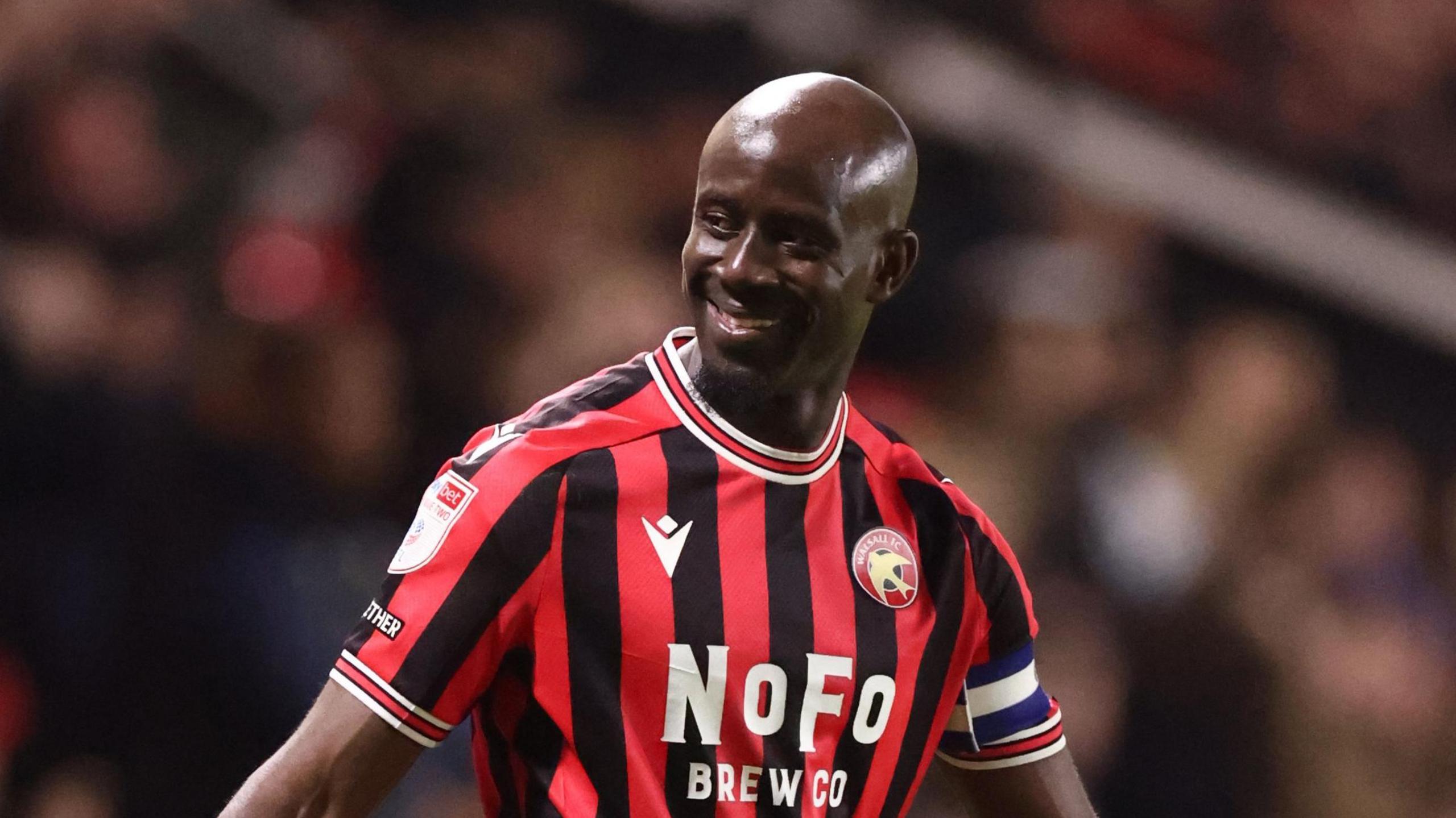 Walsall striker Albert Adomah smiling at fans while playing in a match 