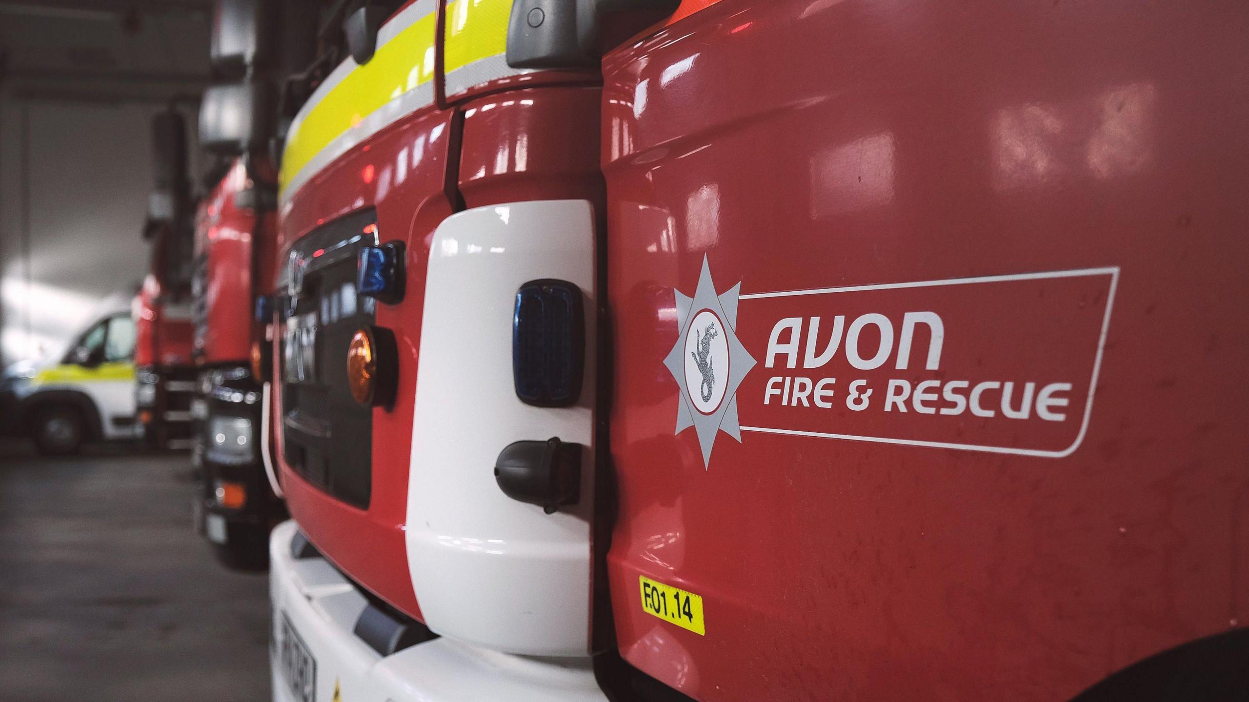 A close-up of the front bumper of a fire service appliance, with Avon Fire & Rescue written on the open door at the front.