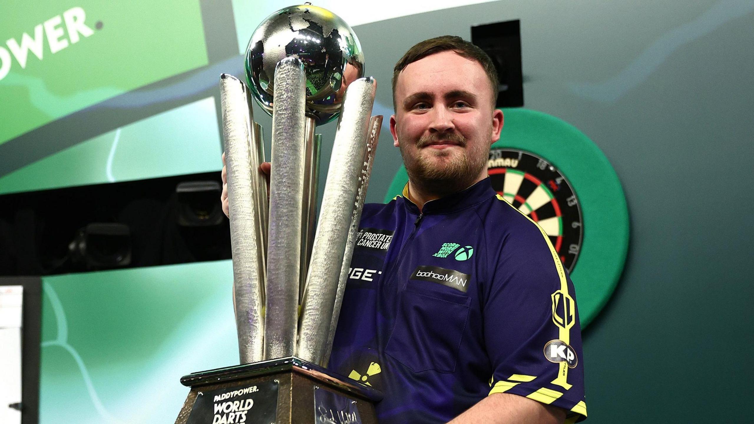 Luke Littler lifts the PDC World Darts Championship trophy at Alexandra Palace