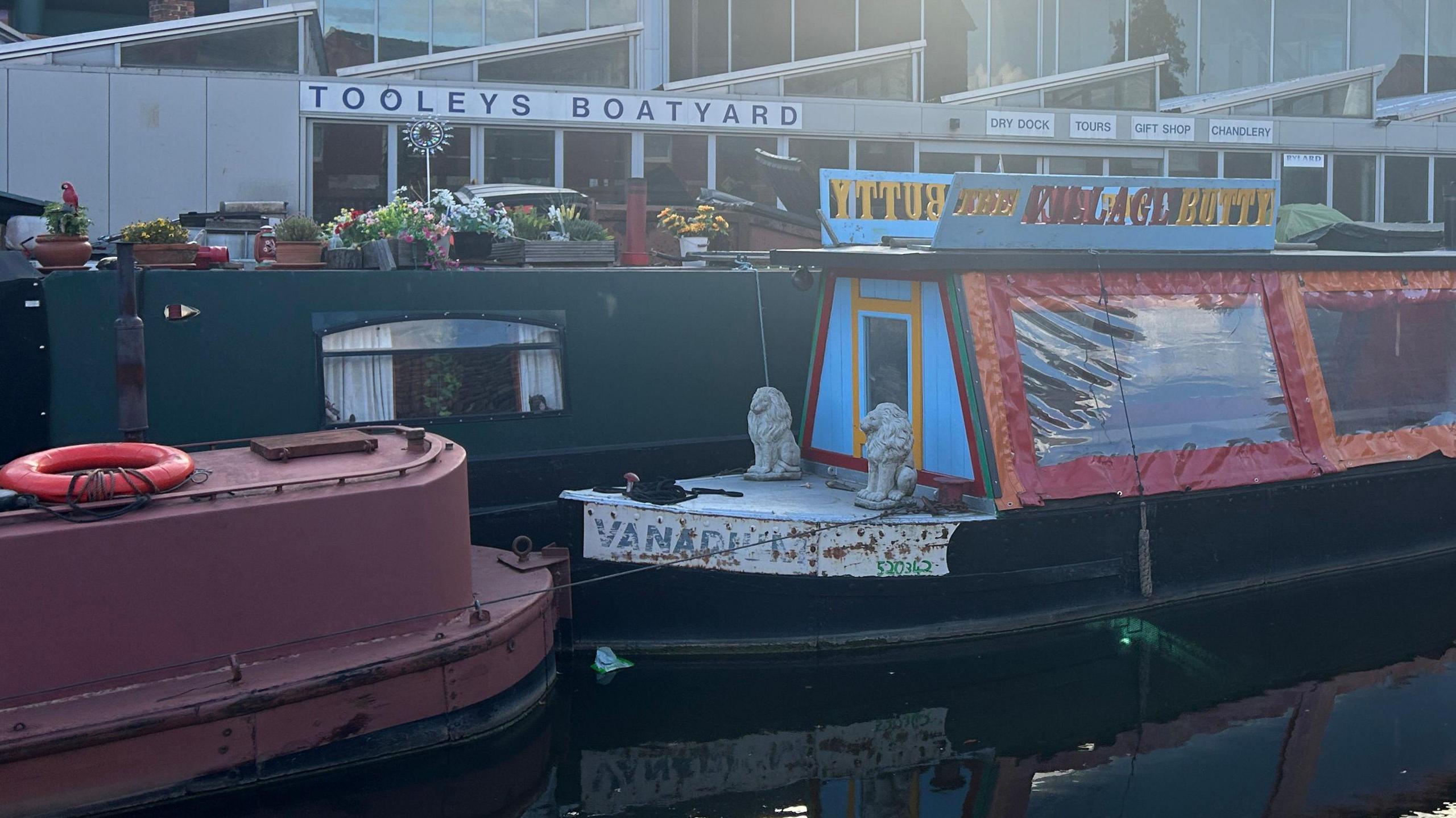 Three colourful canal boats in front of Tooley's Boatyard.