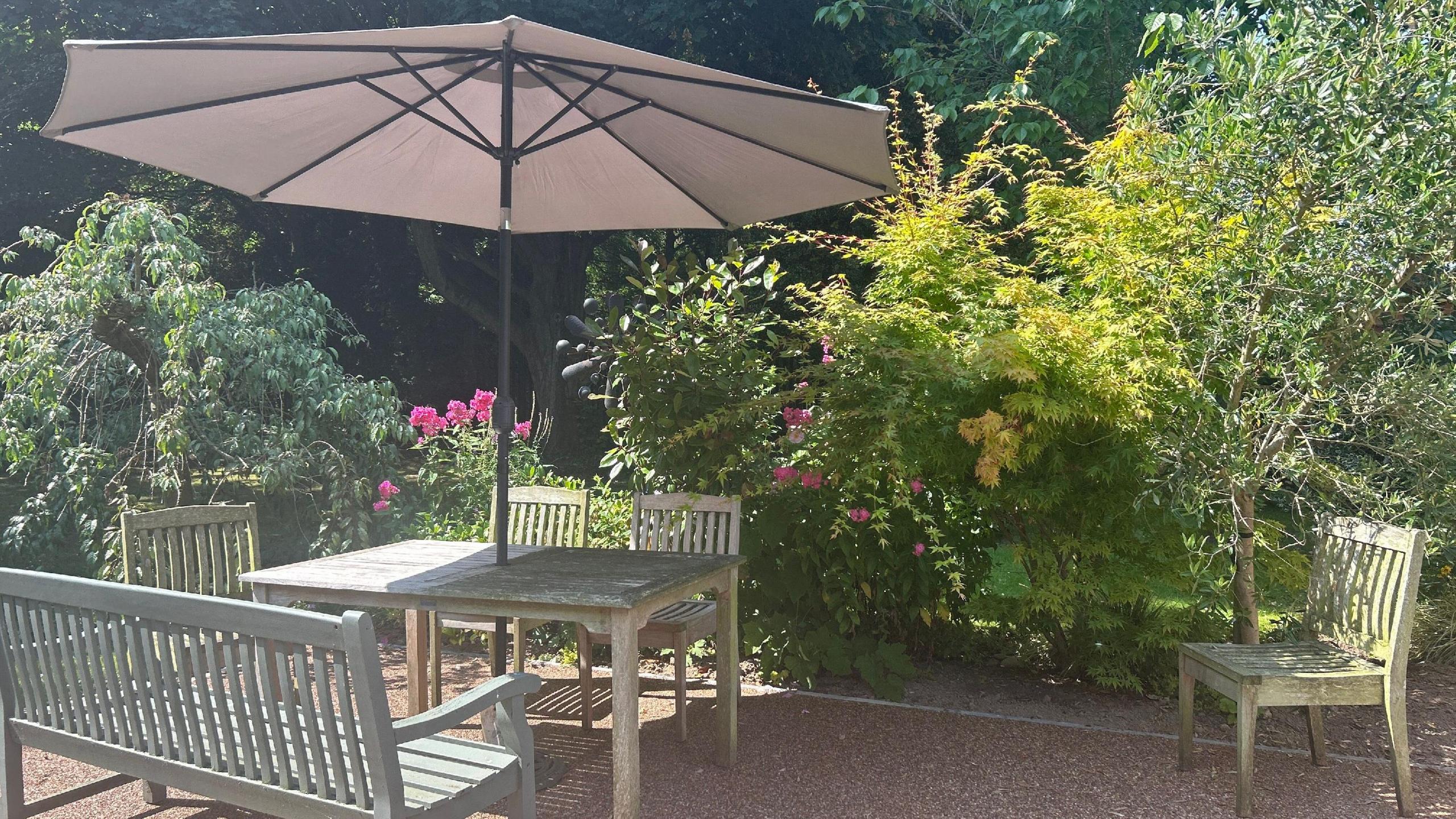 Bench, table, chairs and an umbrella as a palliative care unit's refurbished garden