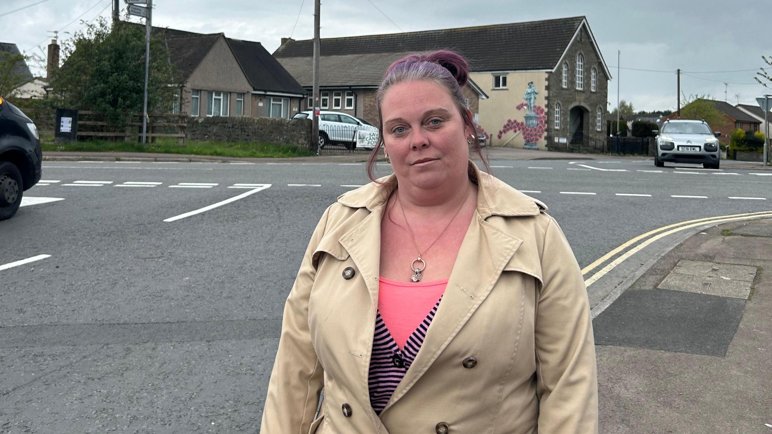 Sarah Brisland standing in front of the crossroads in Broadwell, as cars use it