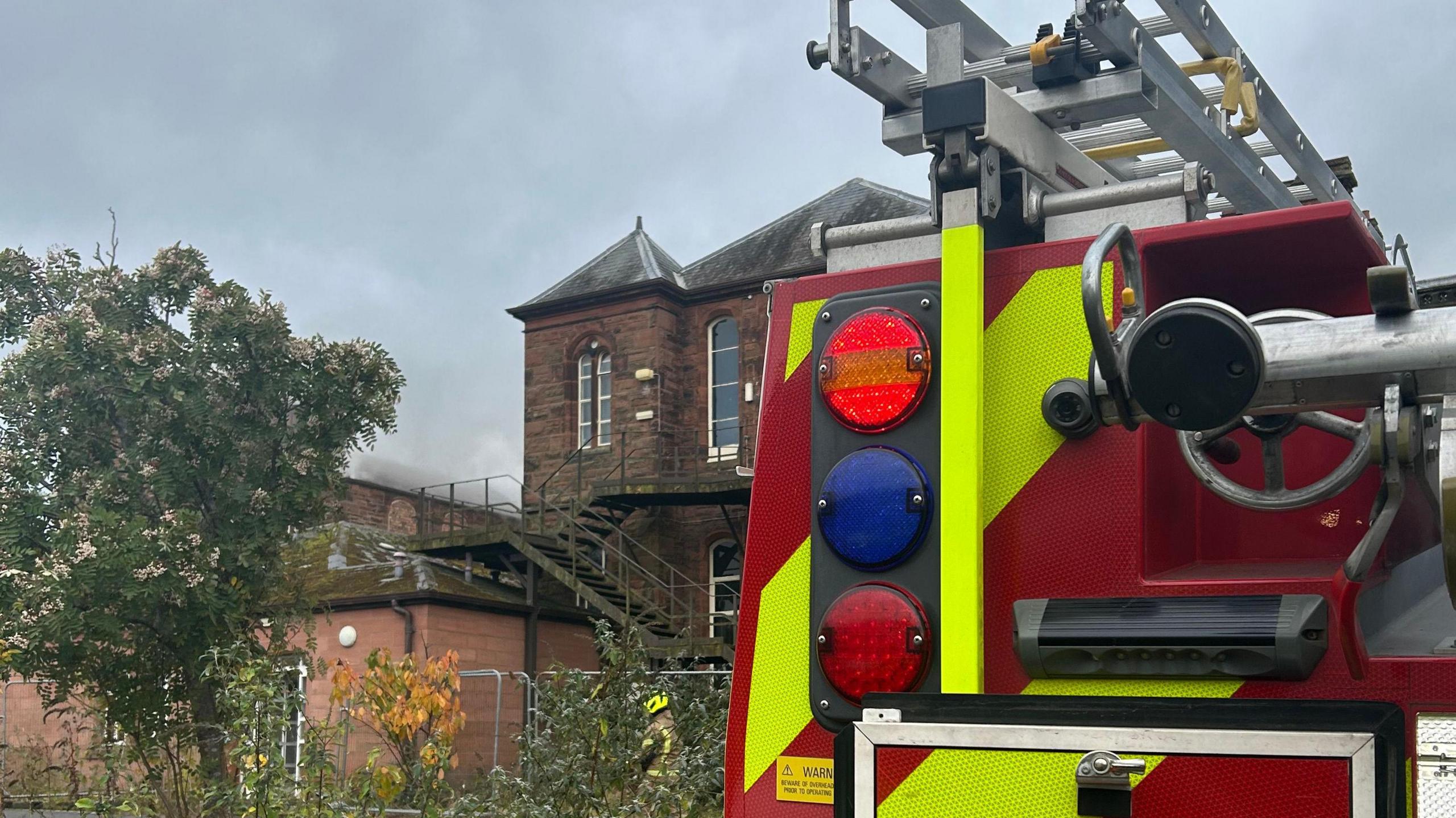 A rear view of a fire engine with an old building in the distance