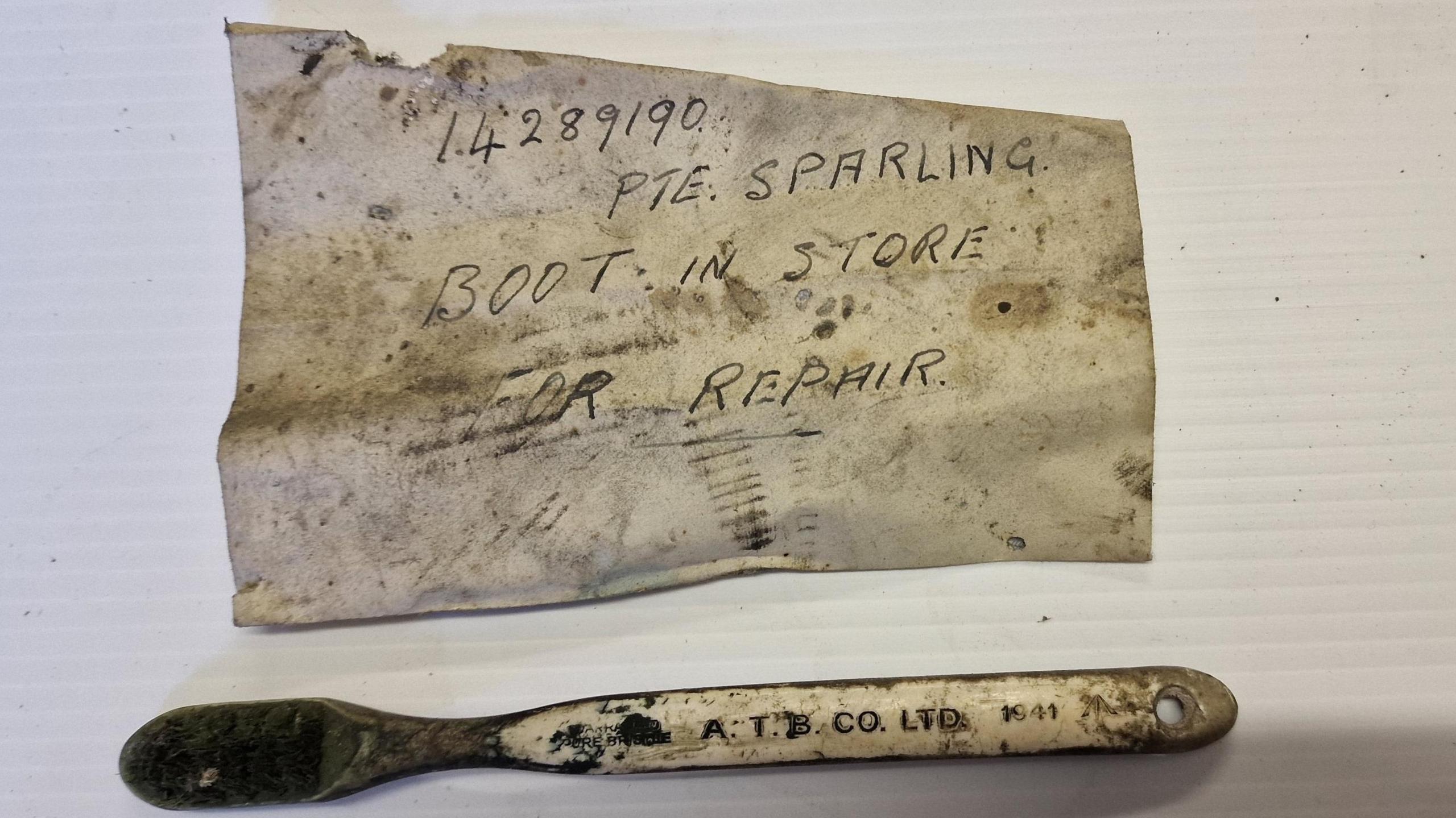 The image shows two items, one a brush with the date 1941 on it and the other a scrap of paper with a note on it saying the boot was ready for repair 