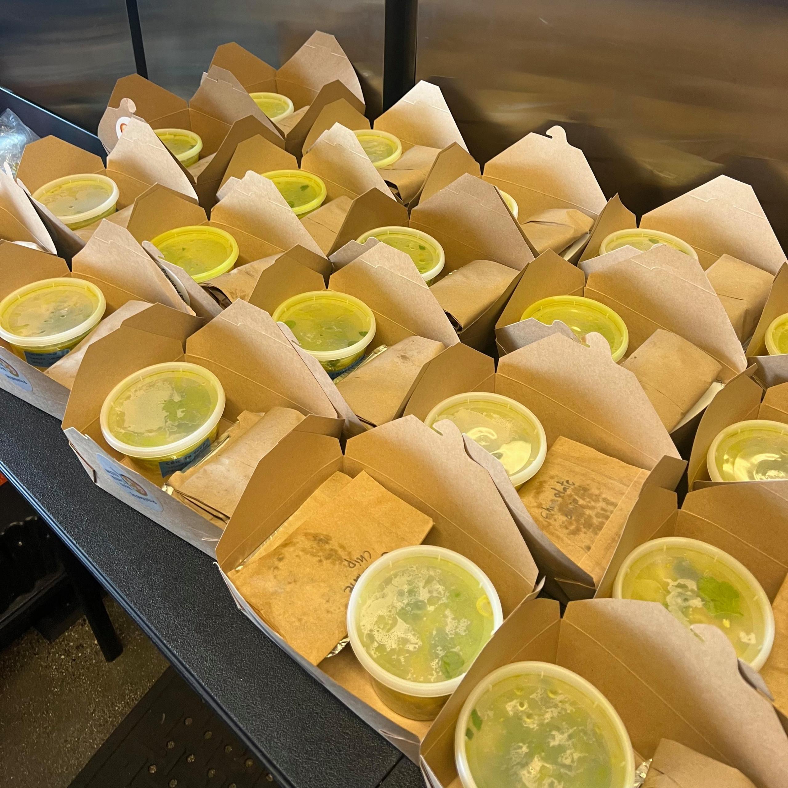 A table is covered with small cardboard boxes containing pots of food.