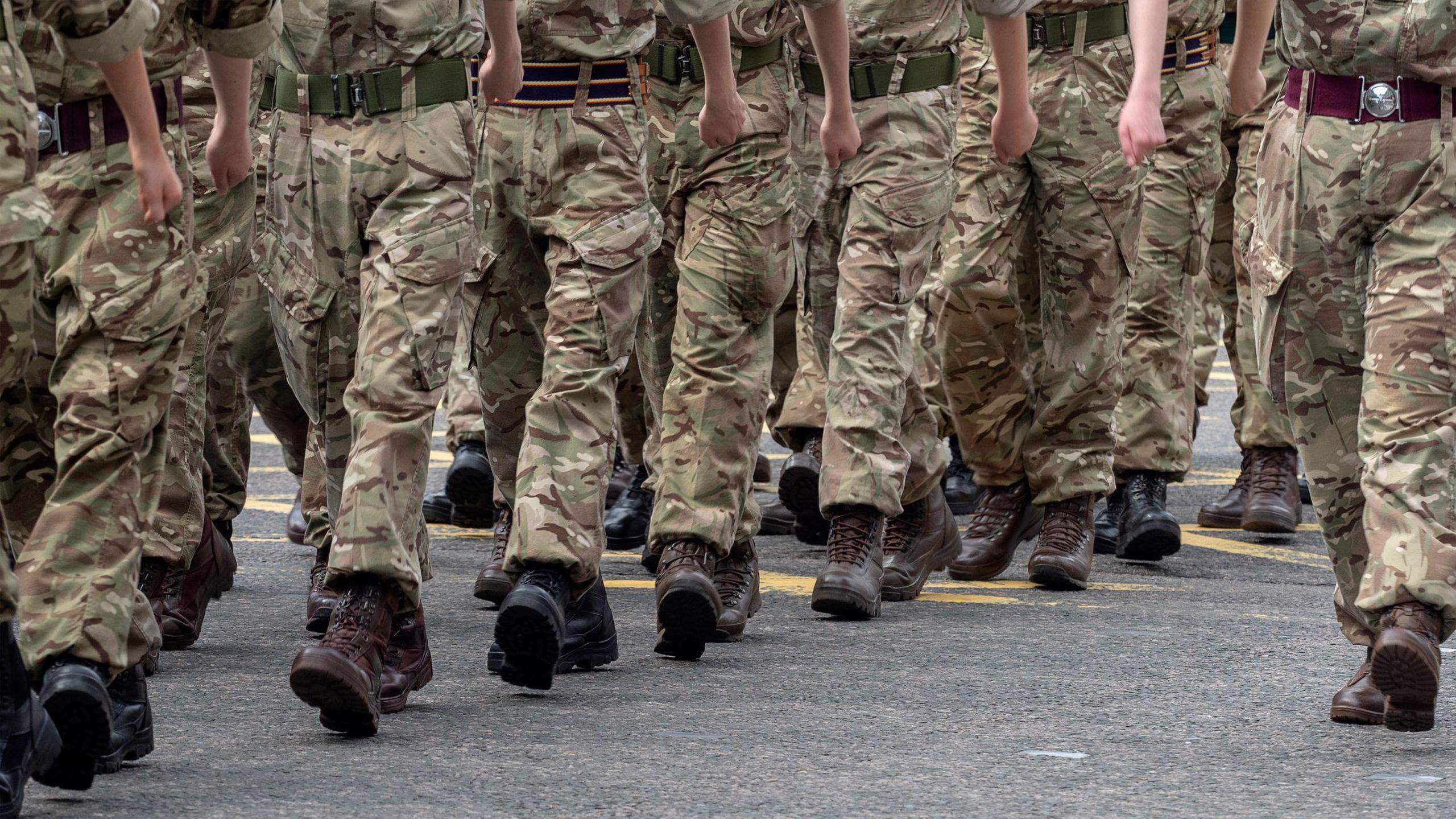 Close up shot of the legs of British soldiers who are in uniform and marching through the street