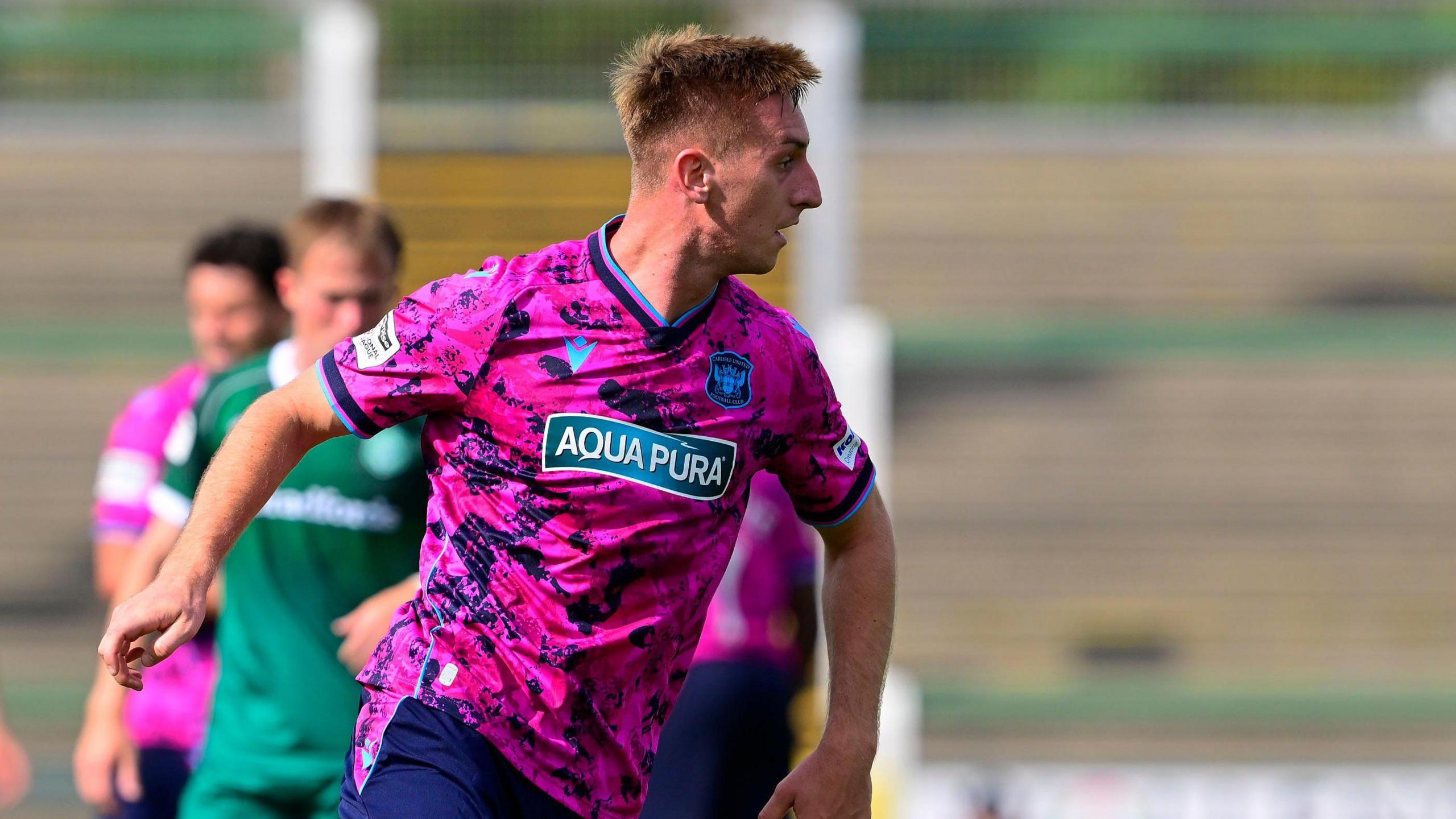 Harvey Bunker playing for Carlisle United in their match away to Yeovil Town, wearing a pink kit 
