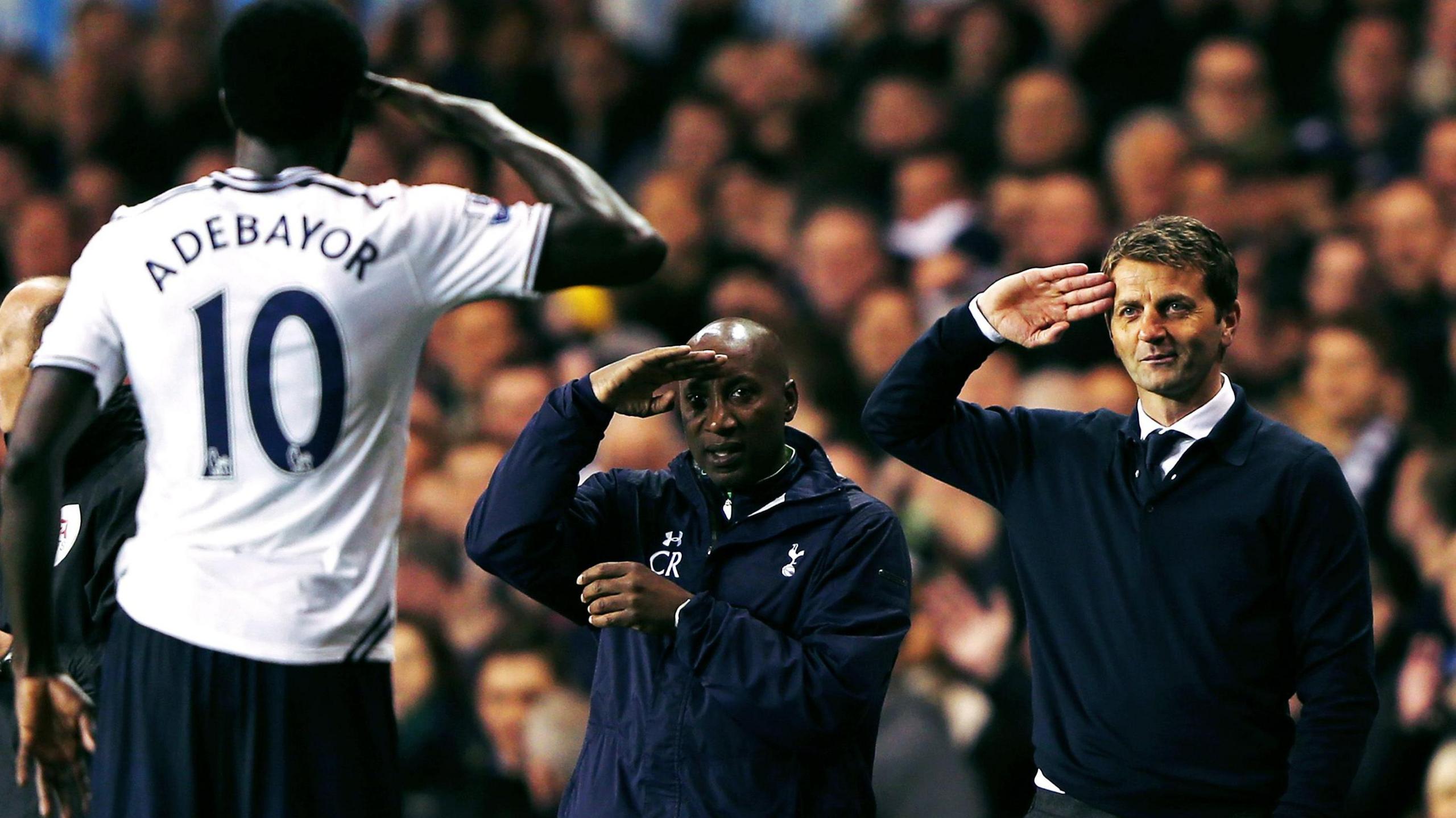 Tottenham striker Emmanuel Adebayor, pictured from behind in a number 10 shirt, gives a salute to coaches Chris Ramsey and Tim Sherwood who reciprocate the gesture