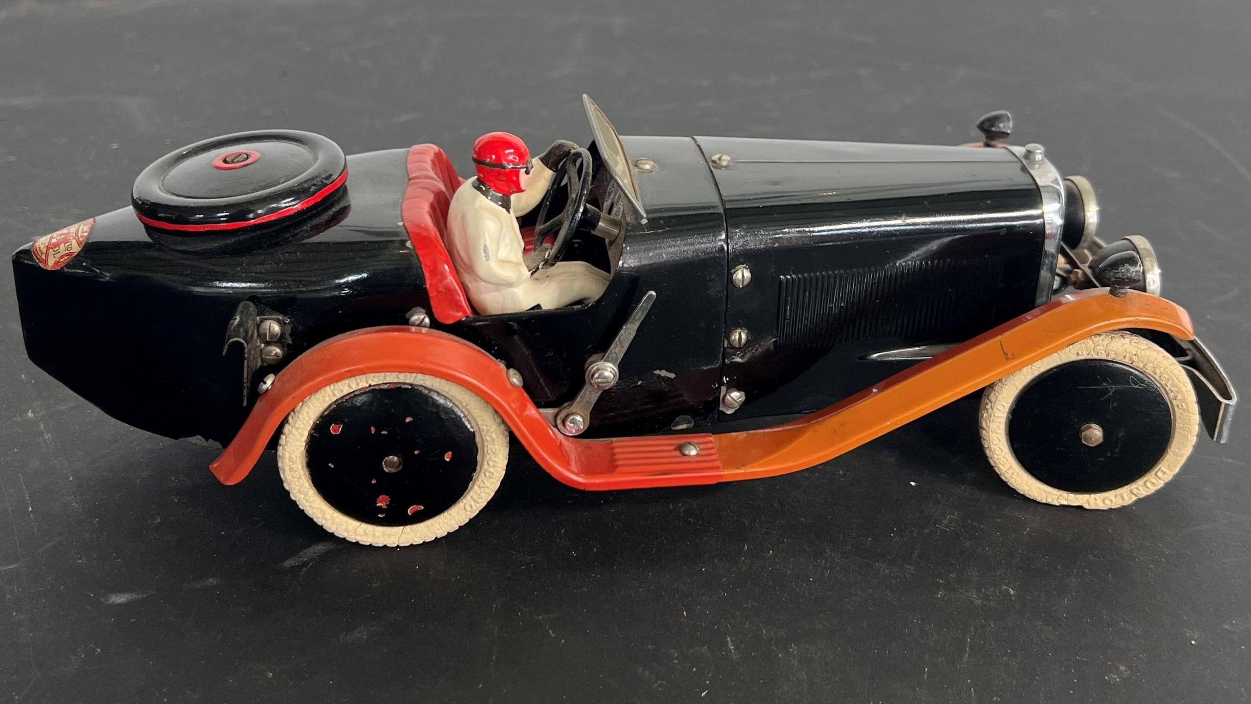 a black 1930s-style Meccano model car with driver in 1930s racing outfit