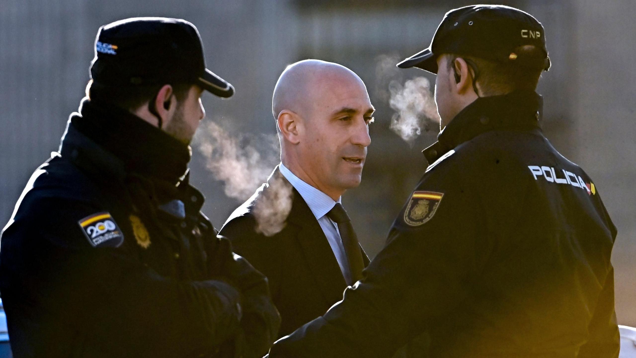 Luis Rubiales stands between two police guards