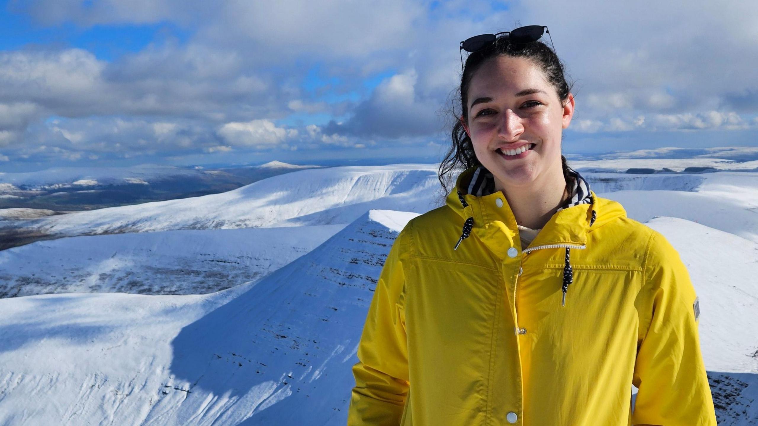 A woman standing in front of a mountain range covered in snow