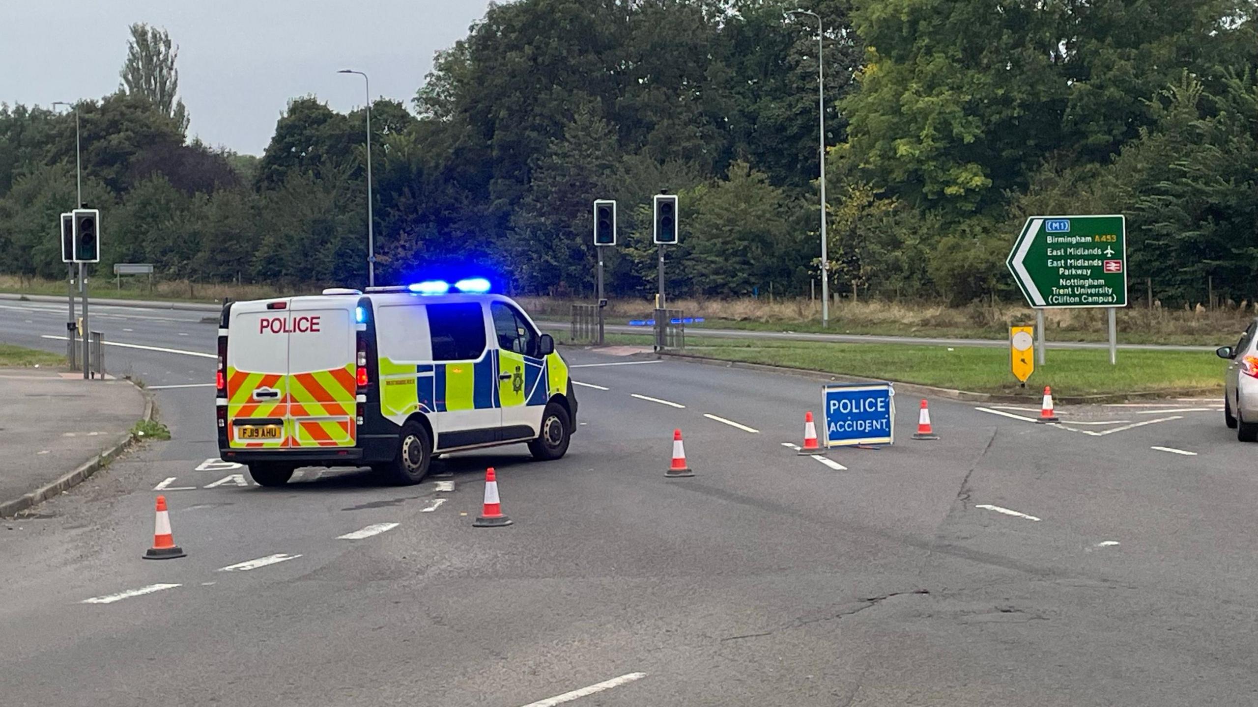 The A453 through Clifton, with a police van blocking the road to traffic, its blue lights flashing.