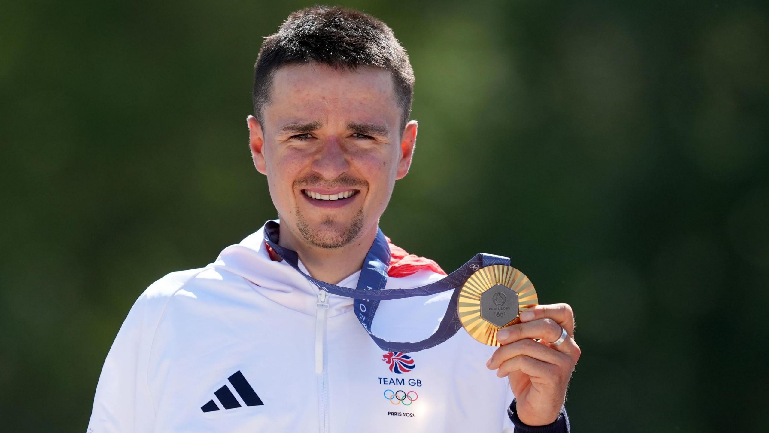 Tom Pidcock holding his gold medal