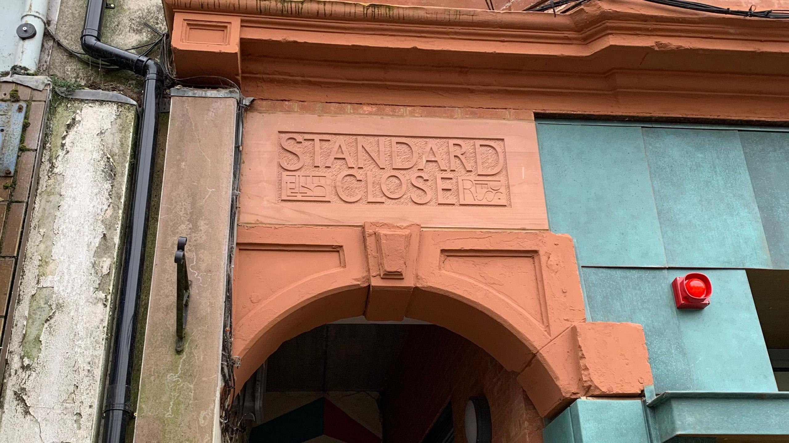 A sandstone sign reading Standard Close is positioned over an archway