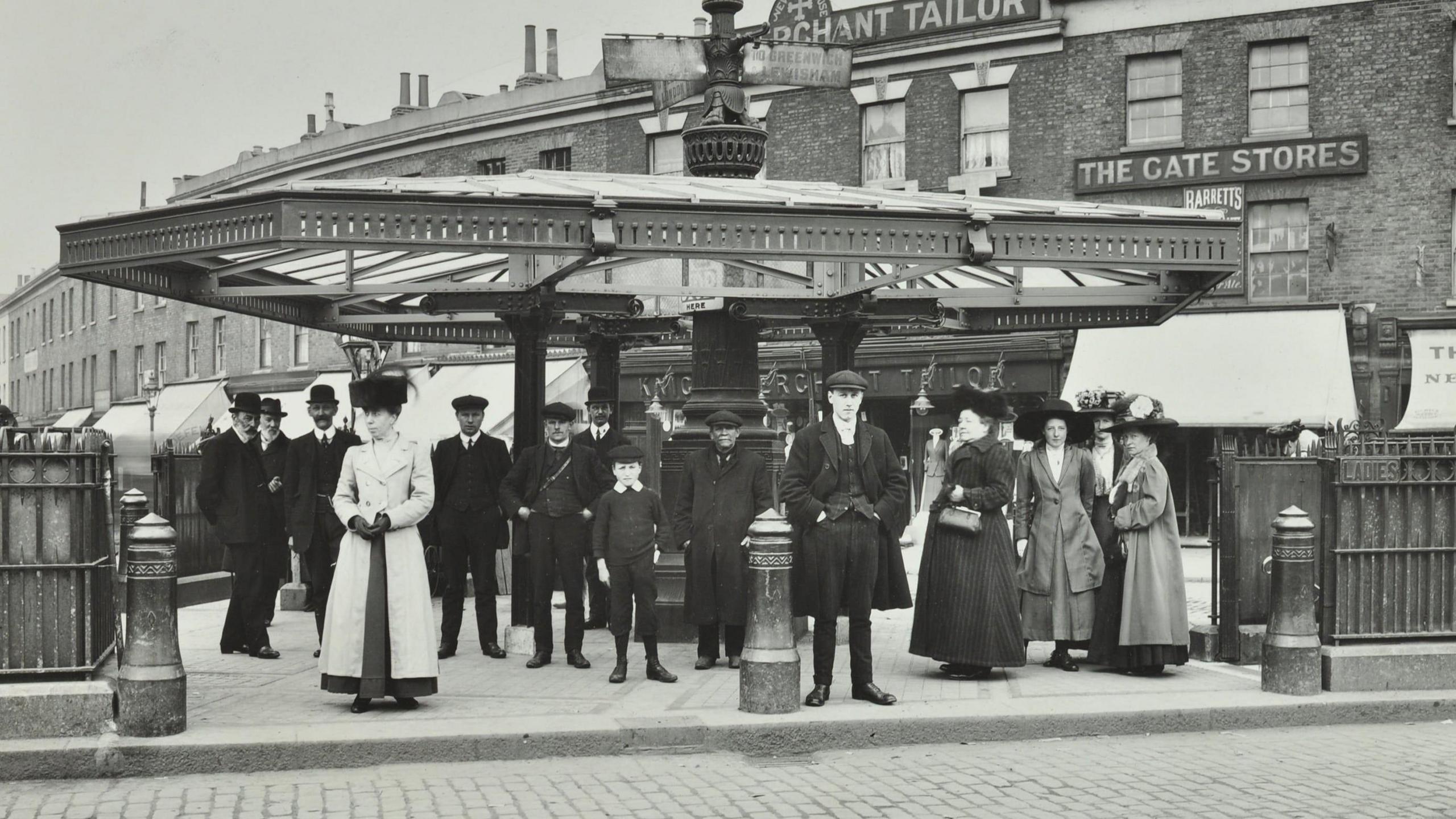 A group of people wait at a tram stop. Black and white photo.