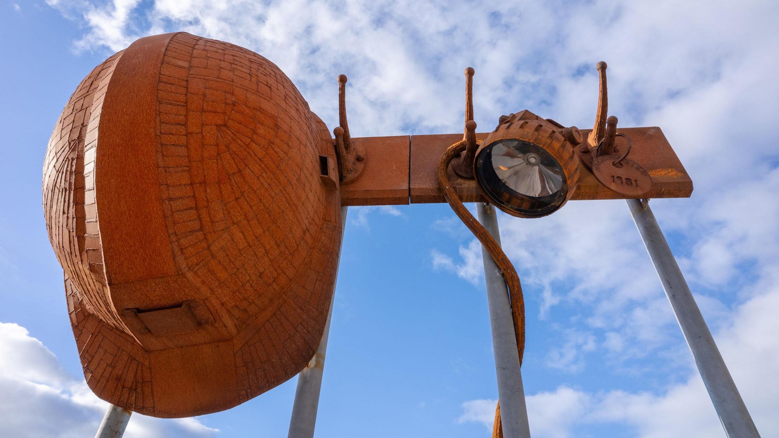 A large miner's helmet and lamp hanging from pegs, created by father-and-son sculptors, Ray and Sam Lonsdale.